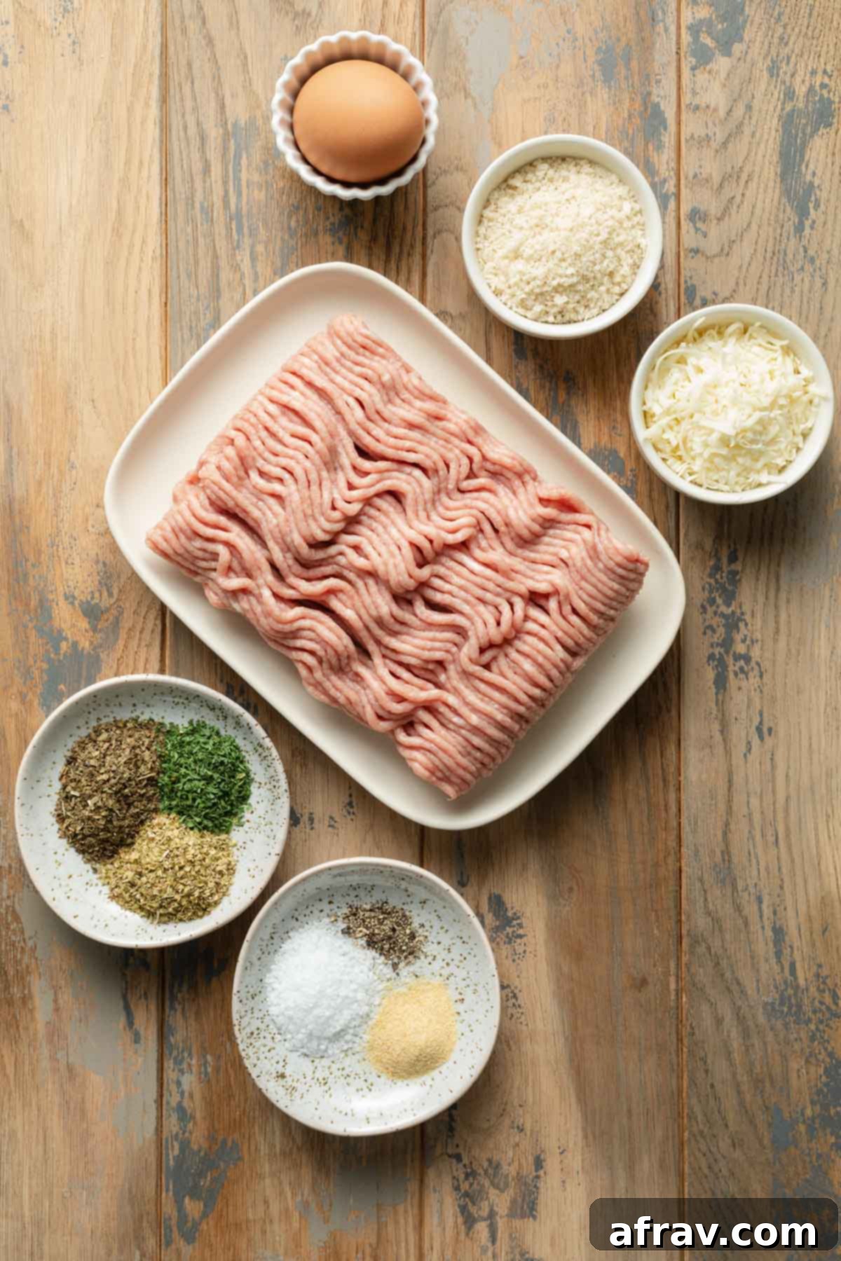 Ingredients to make air fryer turkey meatballs arranged individually on a wooden surface.