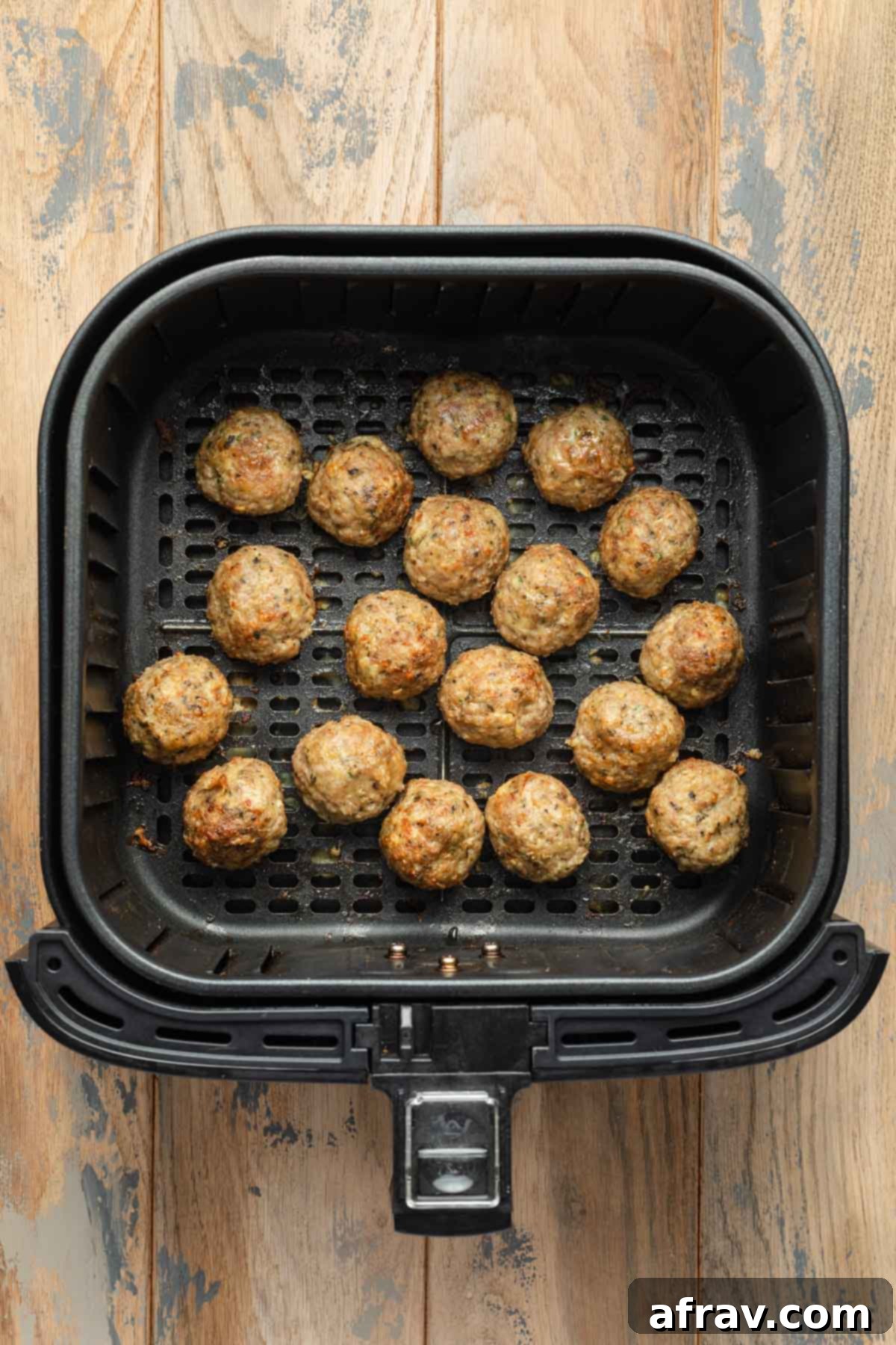 Cooked turkey meatballs in an air fryer basket.