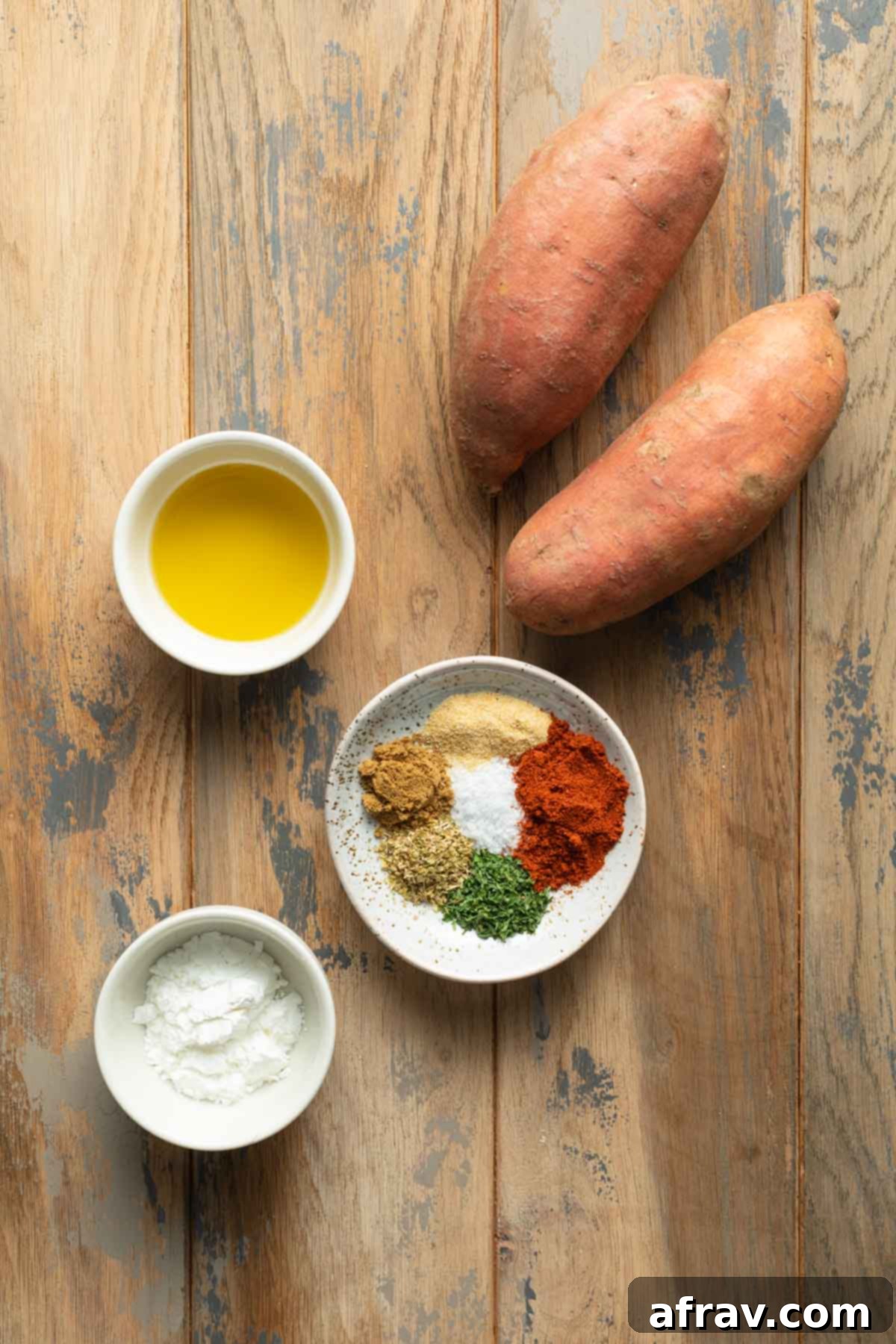 Ingredients to make air fryer sweet potato wedges arranged individually on a wooden surface.