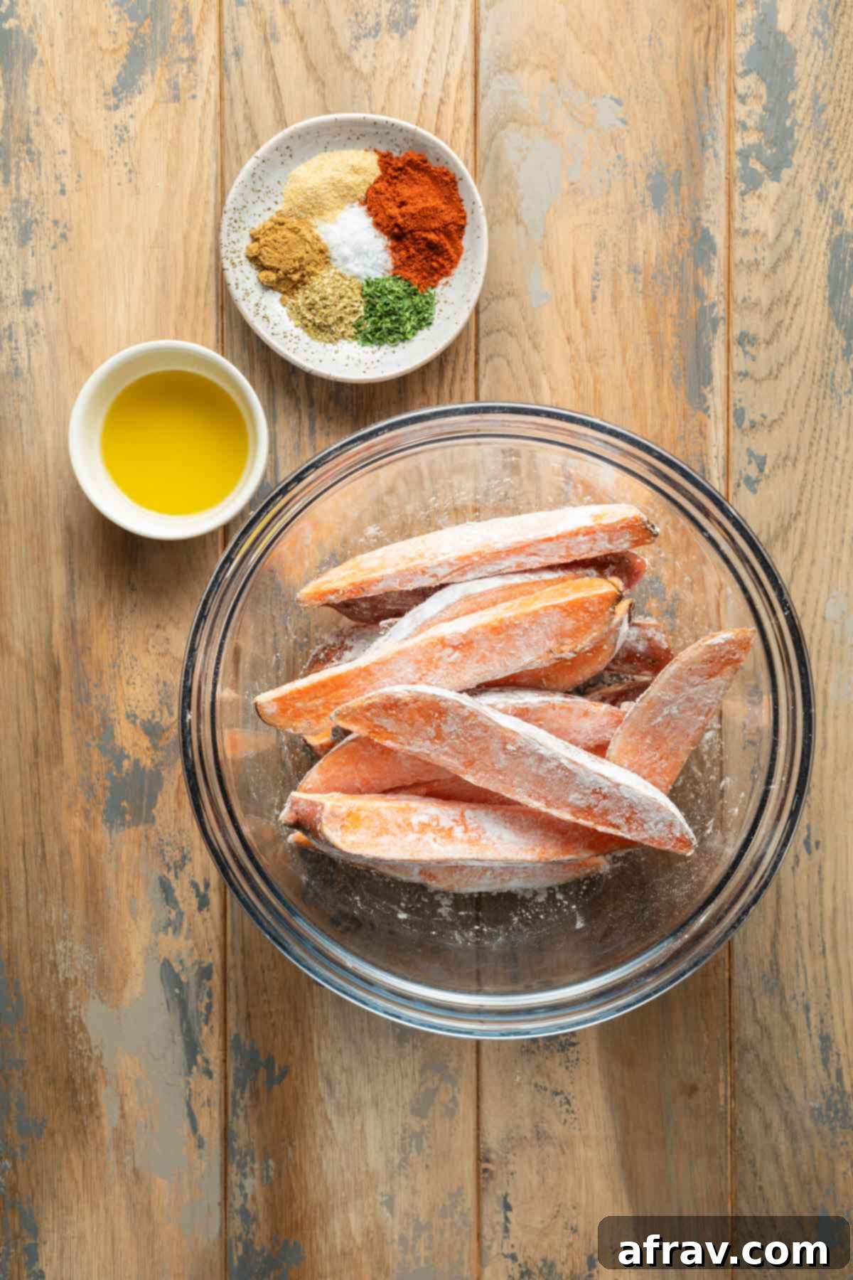 Sweet potato wedges in a glass bowl and coated in cornstarch.