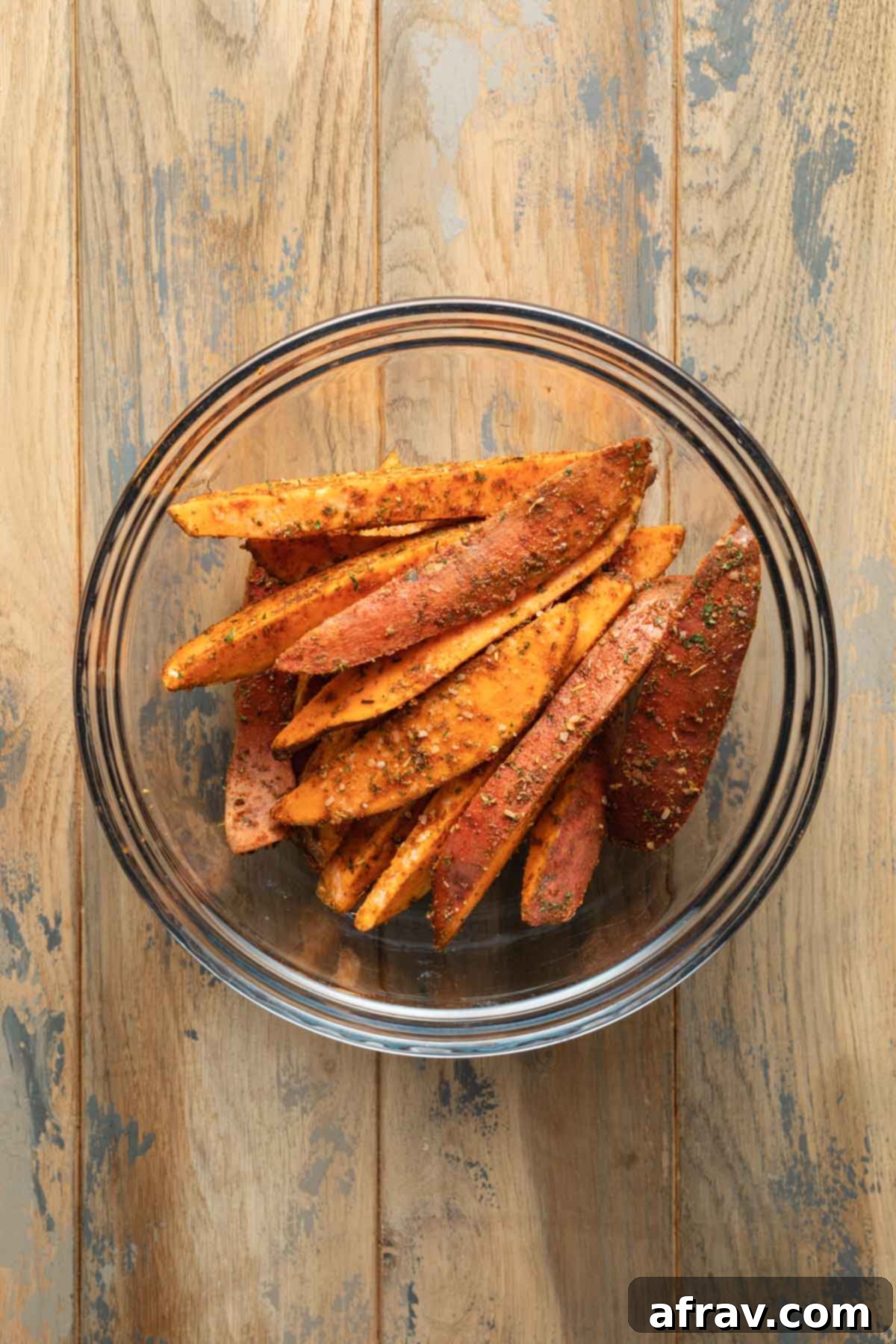 Seasoned sweet potato wedges in a glass bowl.