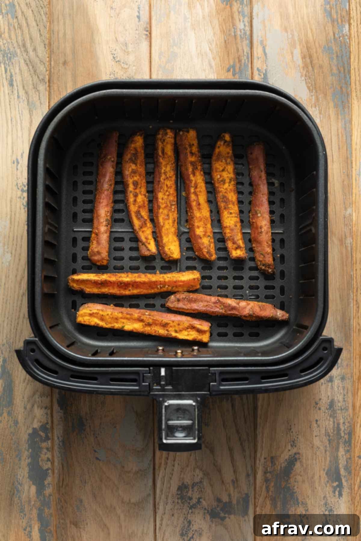 Air fried sweet potato wedges in an air fryer basket.