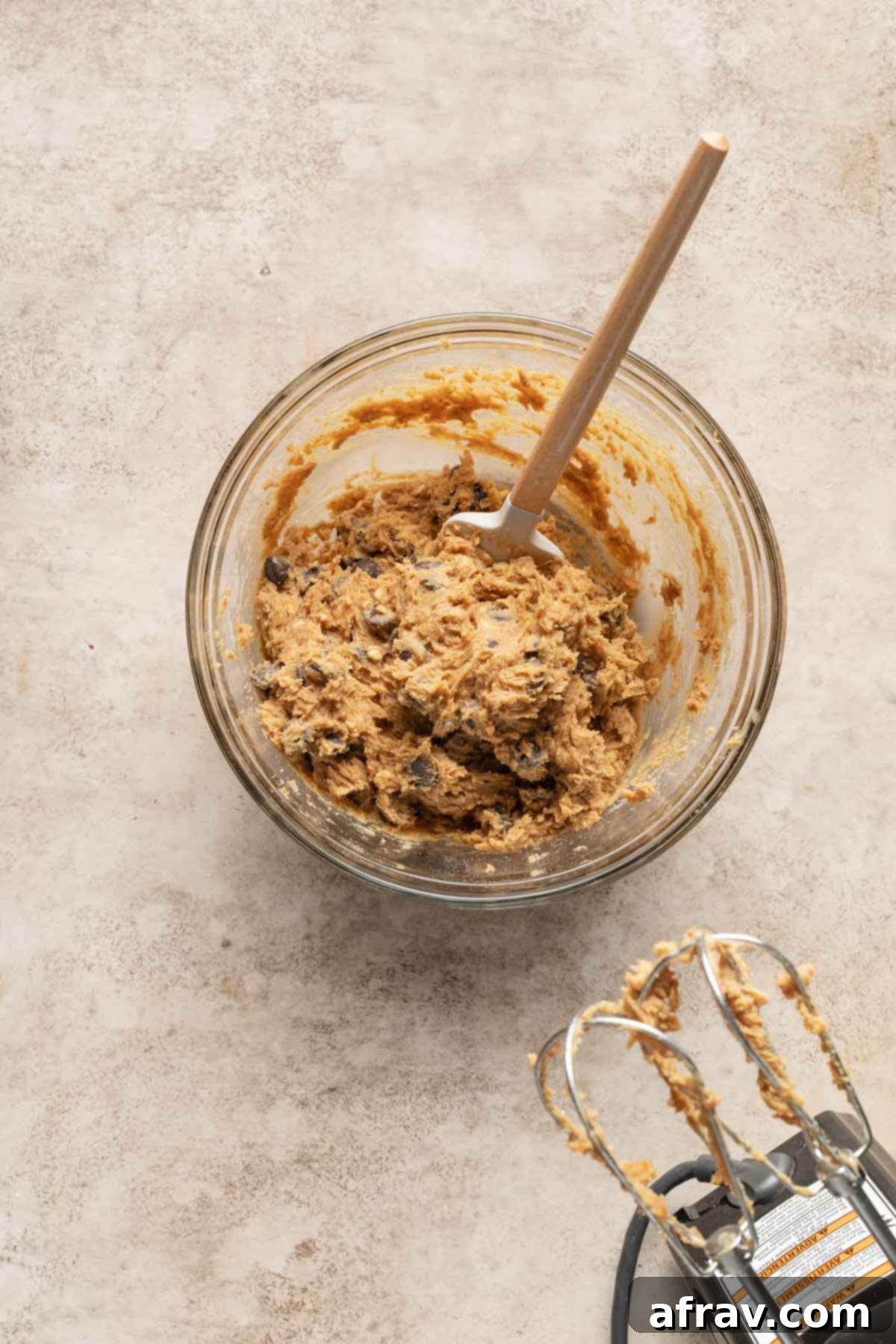 Irresistible Air Fryer Chocolate Chip Cookies 4 Chocolate chip cookie dough in a glass bowl with a spatula inserted into it, ready for scooping.