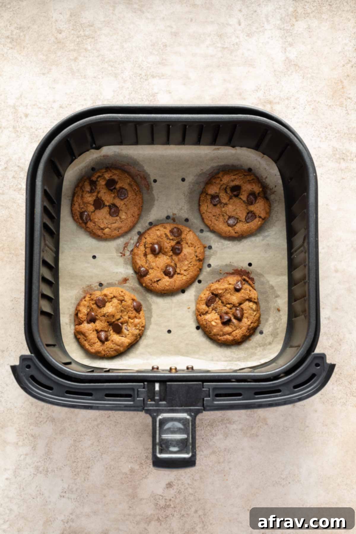 Irresistible Air Fryer Chocolate Chip Cookies 7 Freshly baked air fryer chocolate chip cookies cooling in the air fryer basket after cooking.