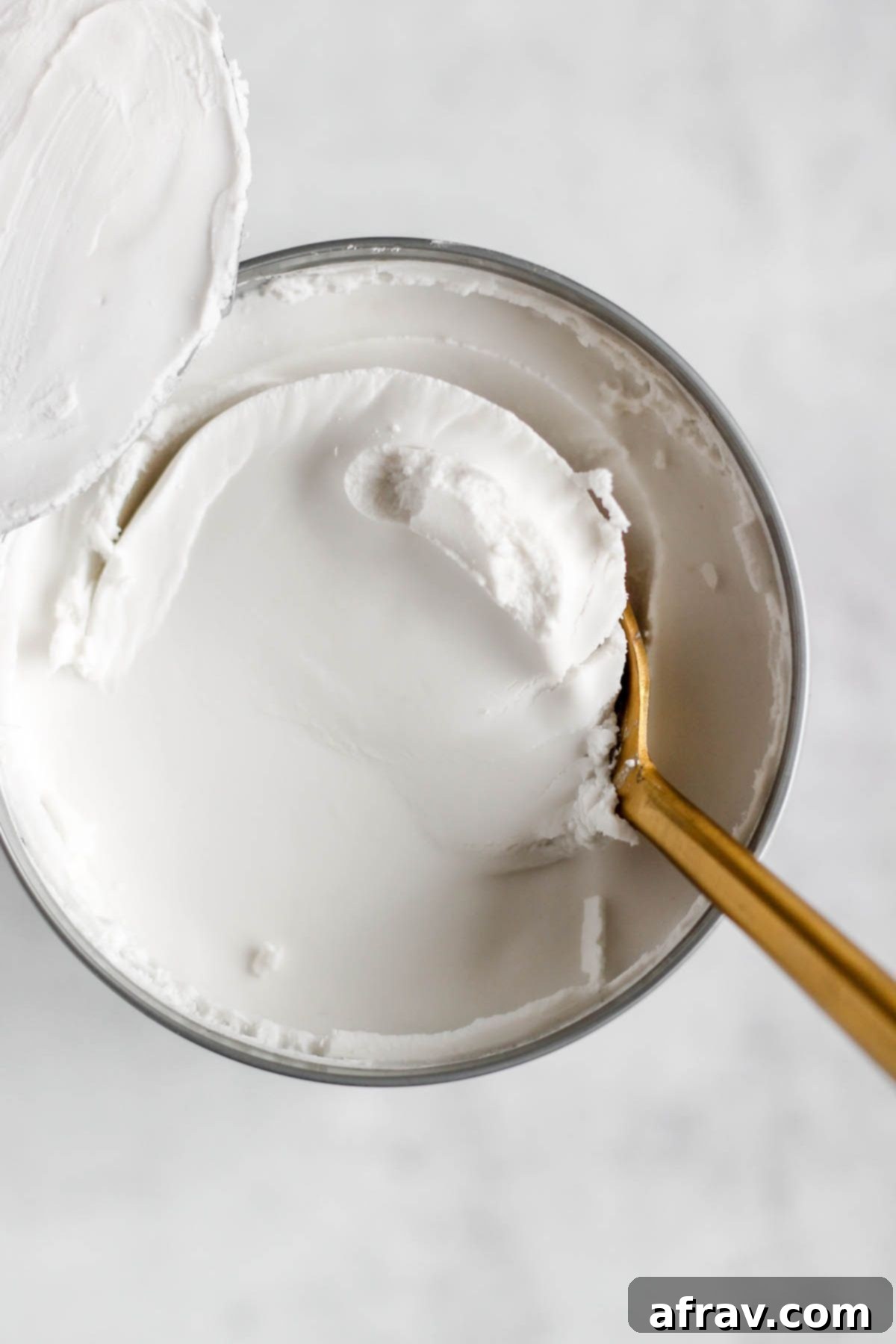 A spoon scooping cream from the top of a can of coconut cream.