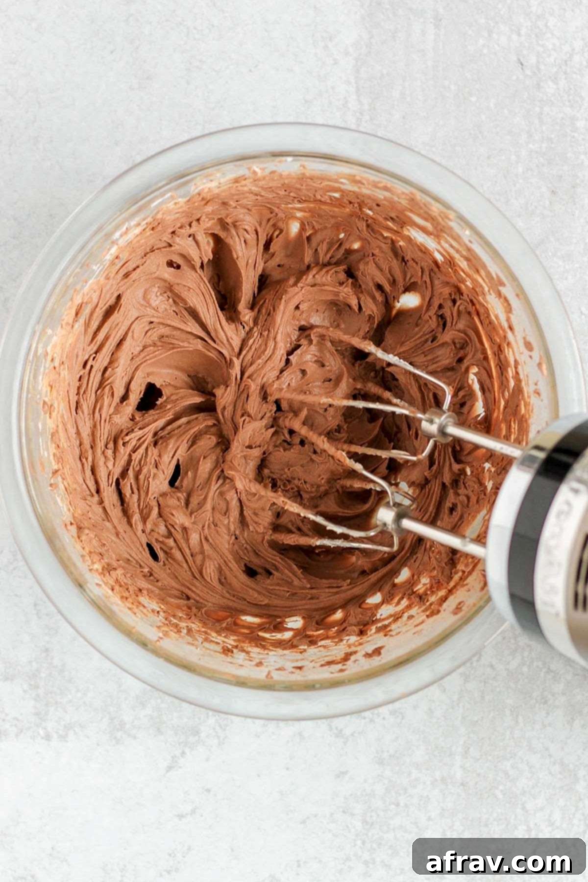 Vegan chocolate mousse whipped in a mixing bowl with a hand-held blender.