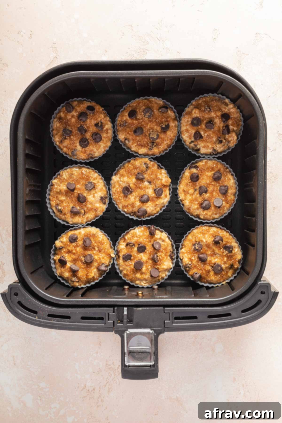 Silicone muffin cups filled with batter and arranged in the air fryer basket.