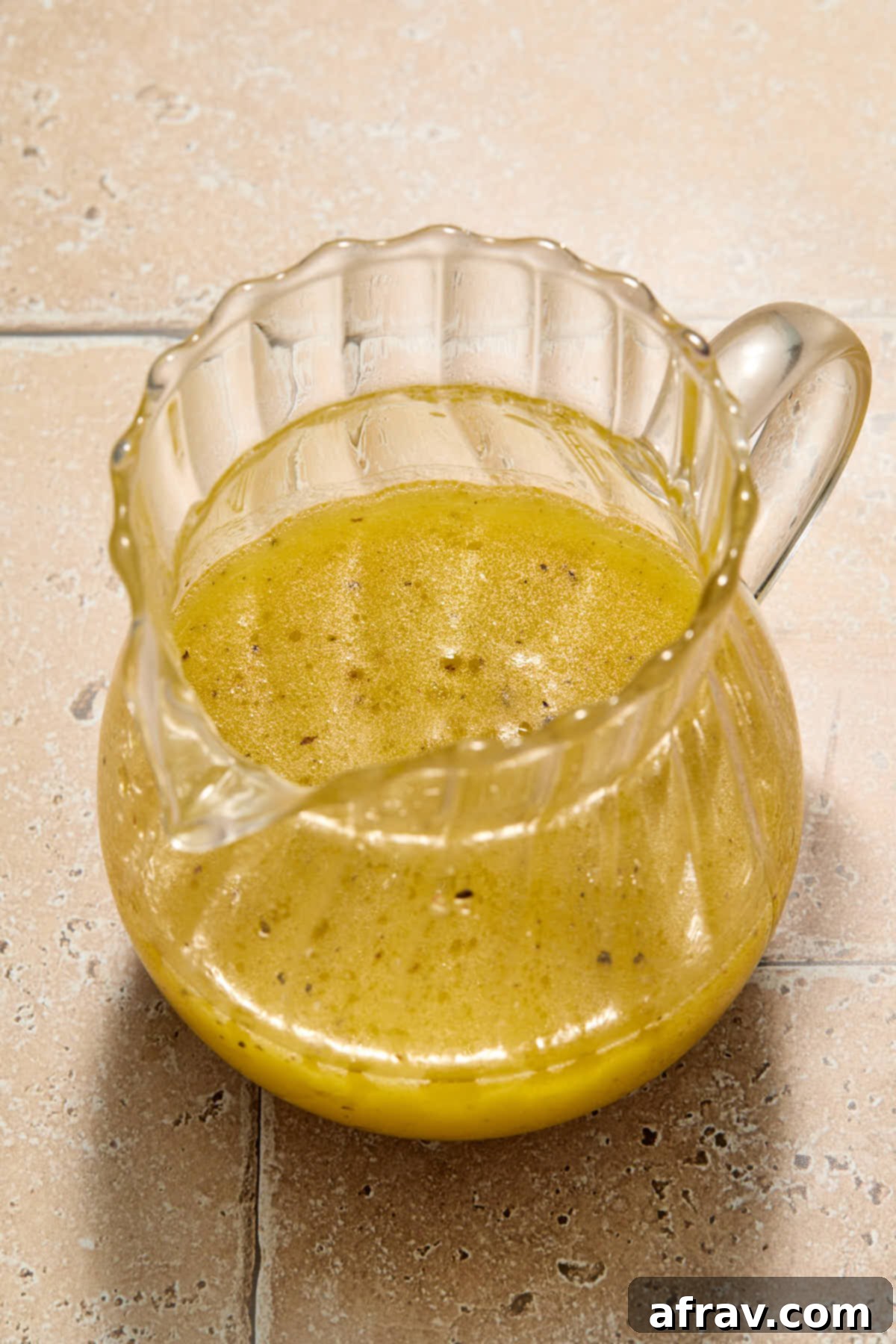 Lemon vinaigrette in a small glass jug, showing the ingredients combined and ready to use.