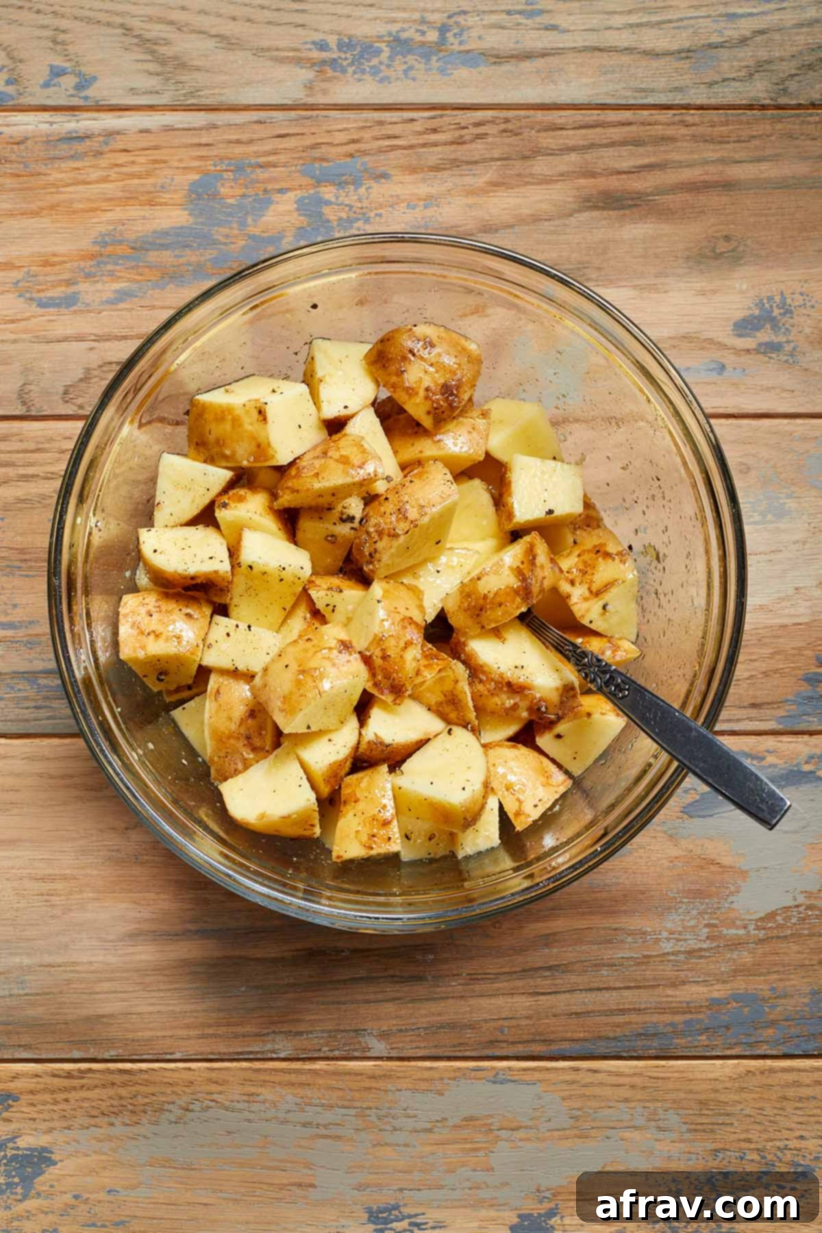Seasoned potato cubes in a glass bowl.