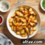 Air fryer home fries in a bowl with a spoon inserted into it.