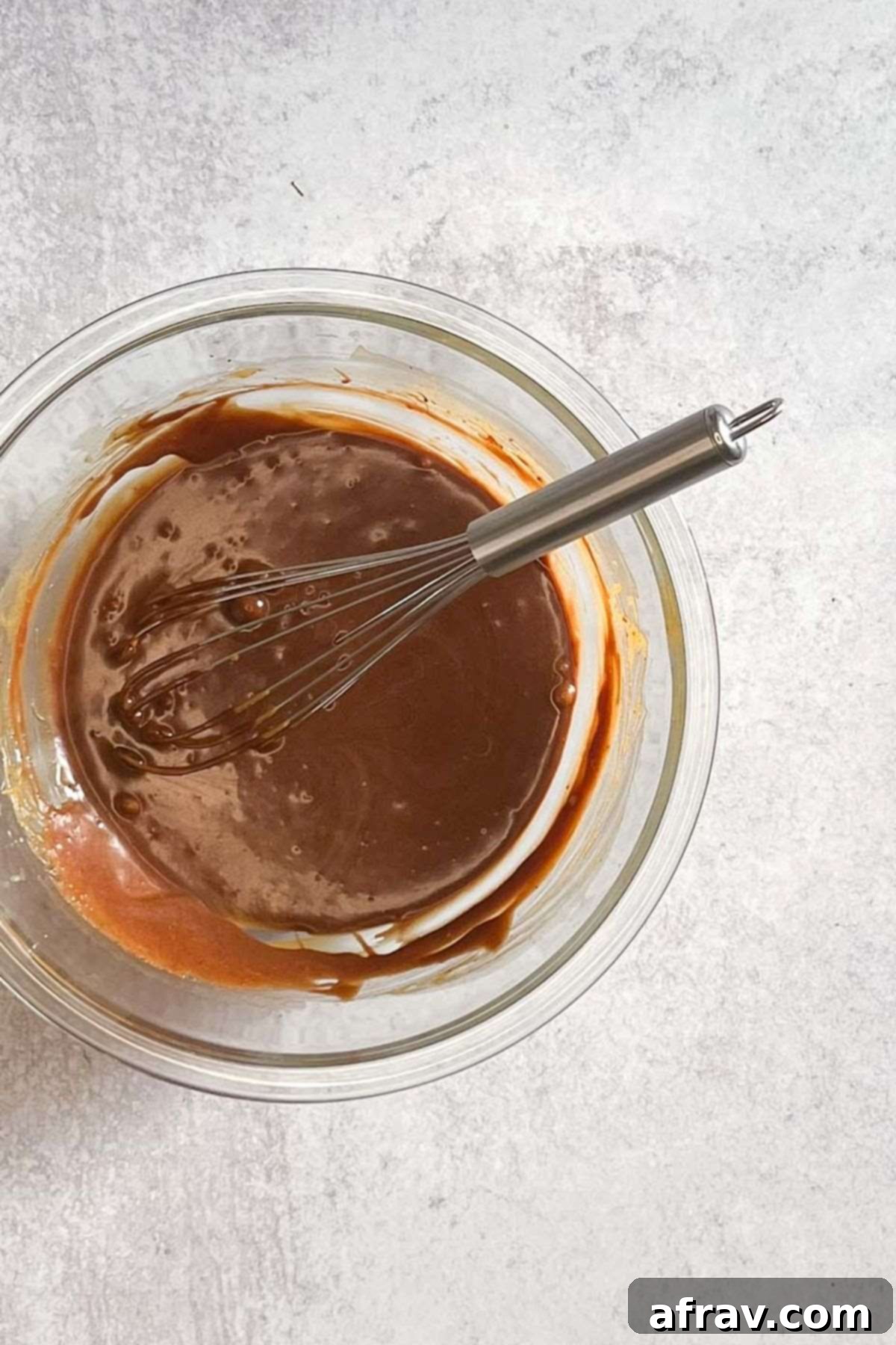 Melted chocolate combined with butter, sugar, and egg mixture in a glass bowl.