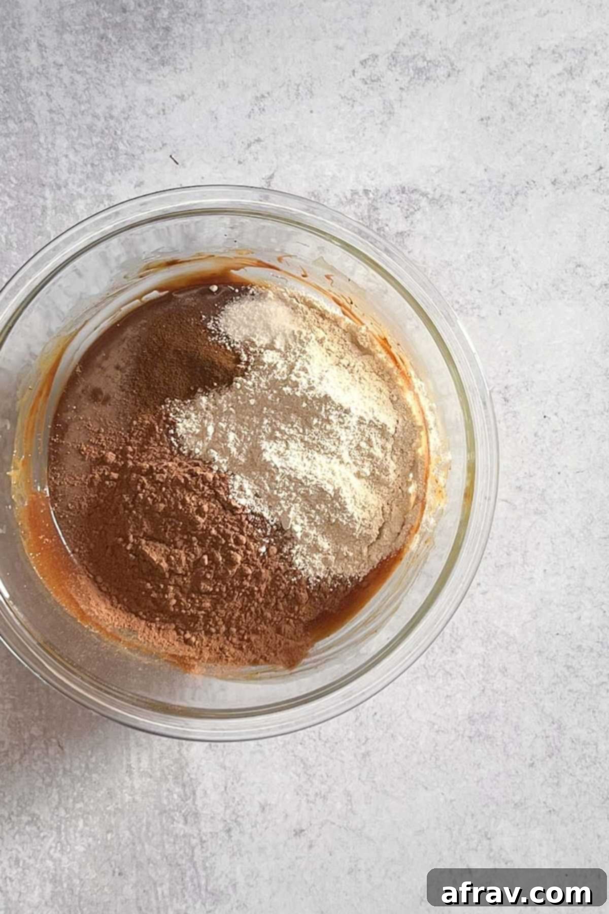 Dry ingredients (oat flour, cacao, espresso, salt) layered over wet brownie batter in a mixing bowl.