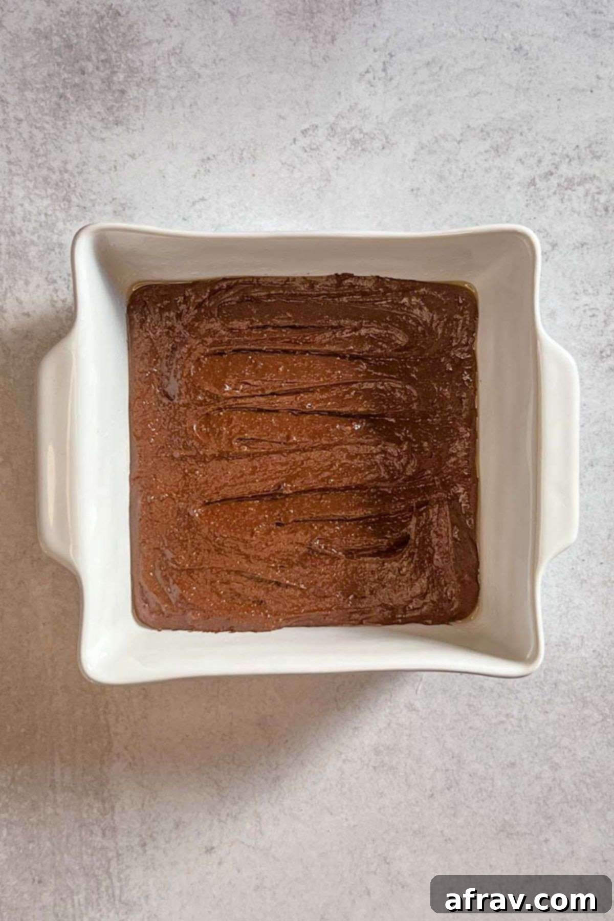 Smooth brownie batter spread evenly in a square 8x8 baking dish.