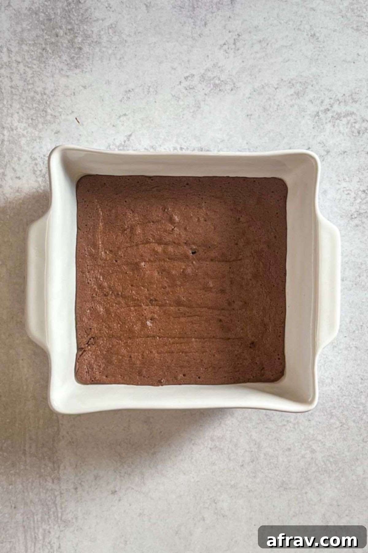 Freshly baked chocolate brownies in a square baking dish, cooling down.