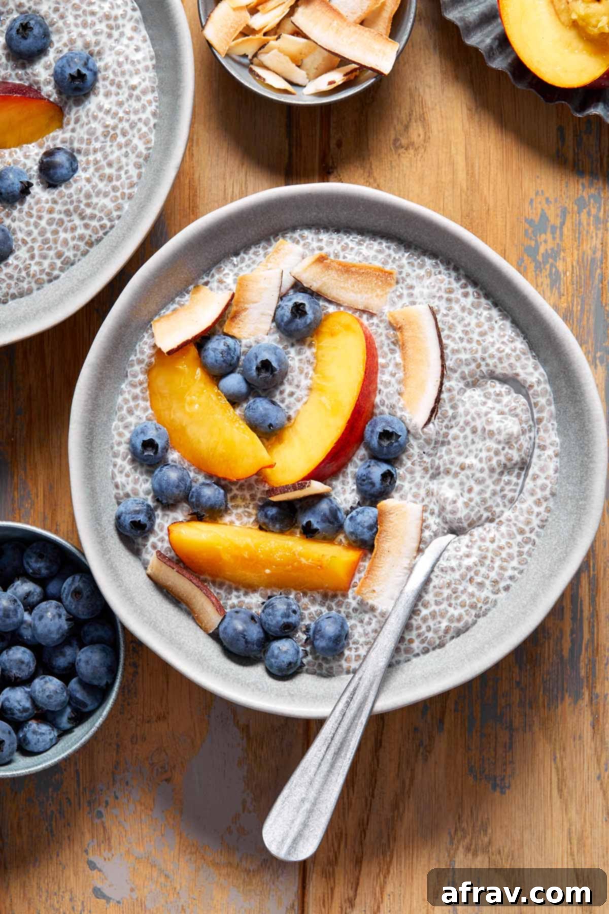 A beautifully arranged bowl of creamy oat milk chia pudding, generously topped with vibrant nectarine slices and fresh blueberries, ready for a healthy breakfast.