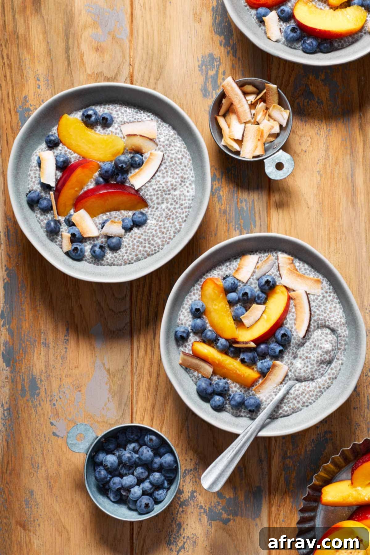 Two beautifully presented bowls of oat milk chia pudding, garnished with fresh berries and fruit, arranged on a wooden table, emphasizing the appeal of a prepared healthy breakfast.