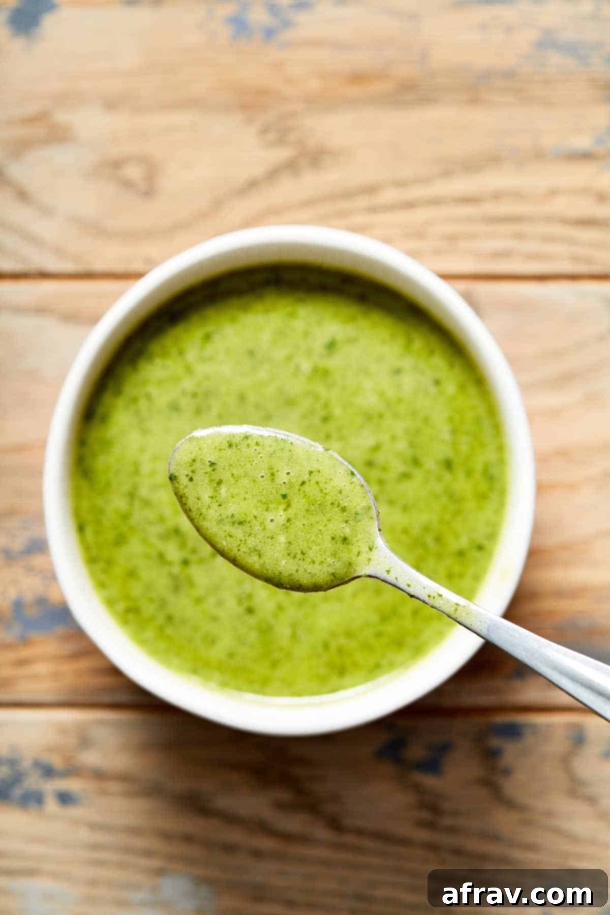Overhead view of a bowl of jalapeño vinaigrette with a spoonful lifted out to show the texture.