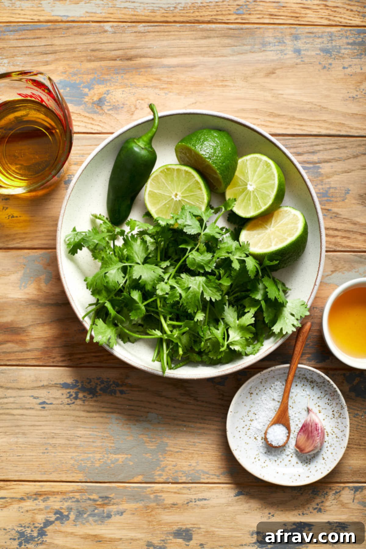 Ingredients to make jalapeño vinaigrette arranged individually on a wooden table.