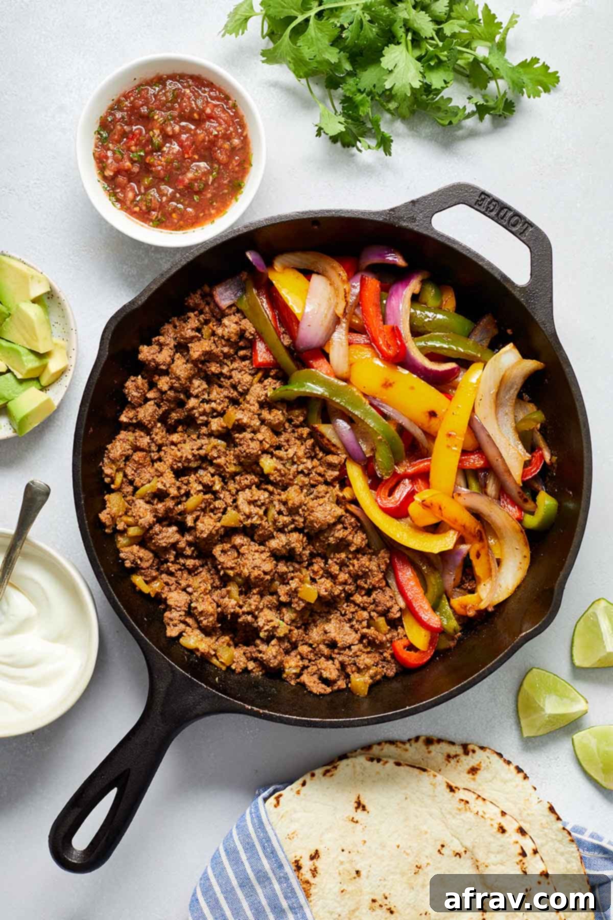 Zesty Ground Beef Fajitas 6 Ground beef, peppers and onions in a cast iron pan with fajita toppings surrounding it.