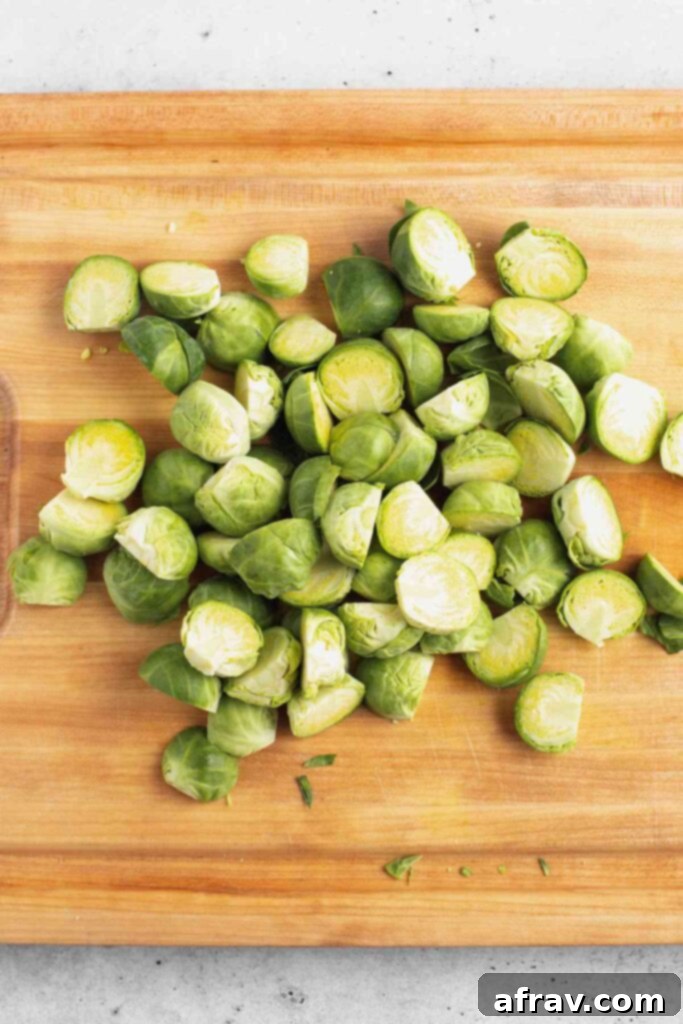 Honey Glazed Brussels Sprouts with Tangy Goat Cheese 5 Sliced Brussels sprouts on a wood cutting board, ready for cooking.
