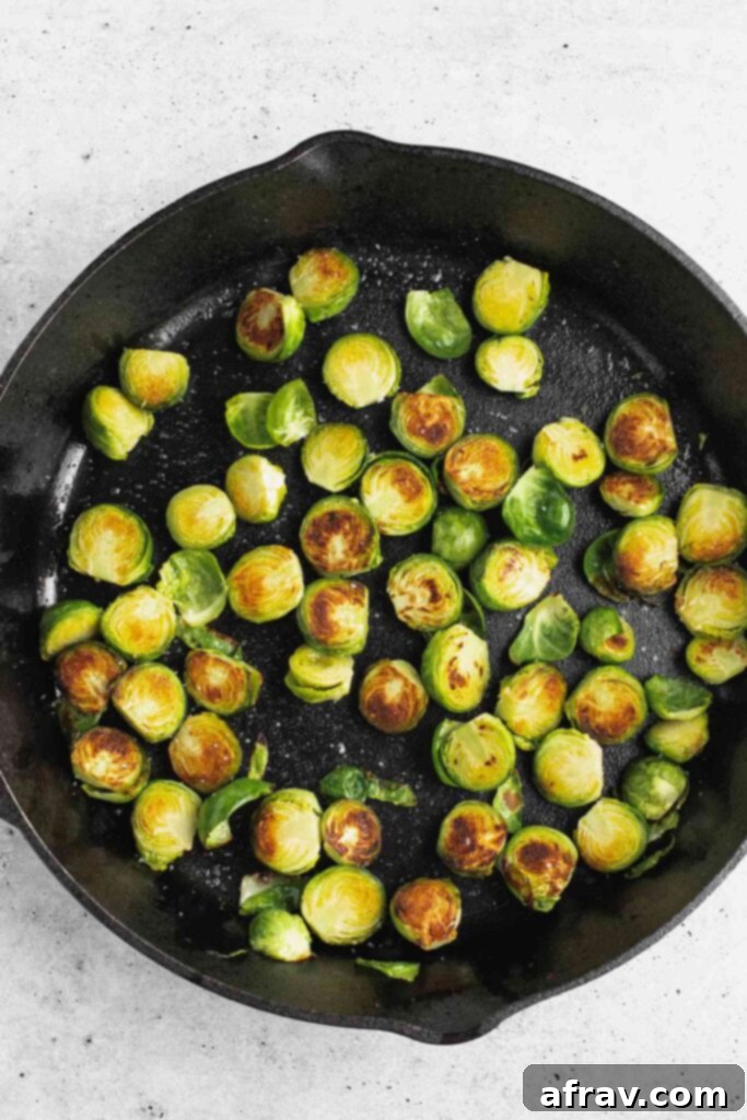 Sliced and roasted Brussels sprouts in a cast iron skillet, demonstrating their browned and crisp texture post-oven.