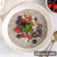 Chia bowl topped with fresh blueberries, raspberries, and chopped almonds with two vintage spoons in the bowl.