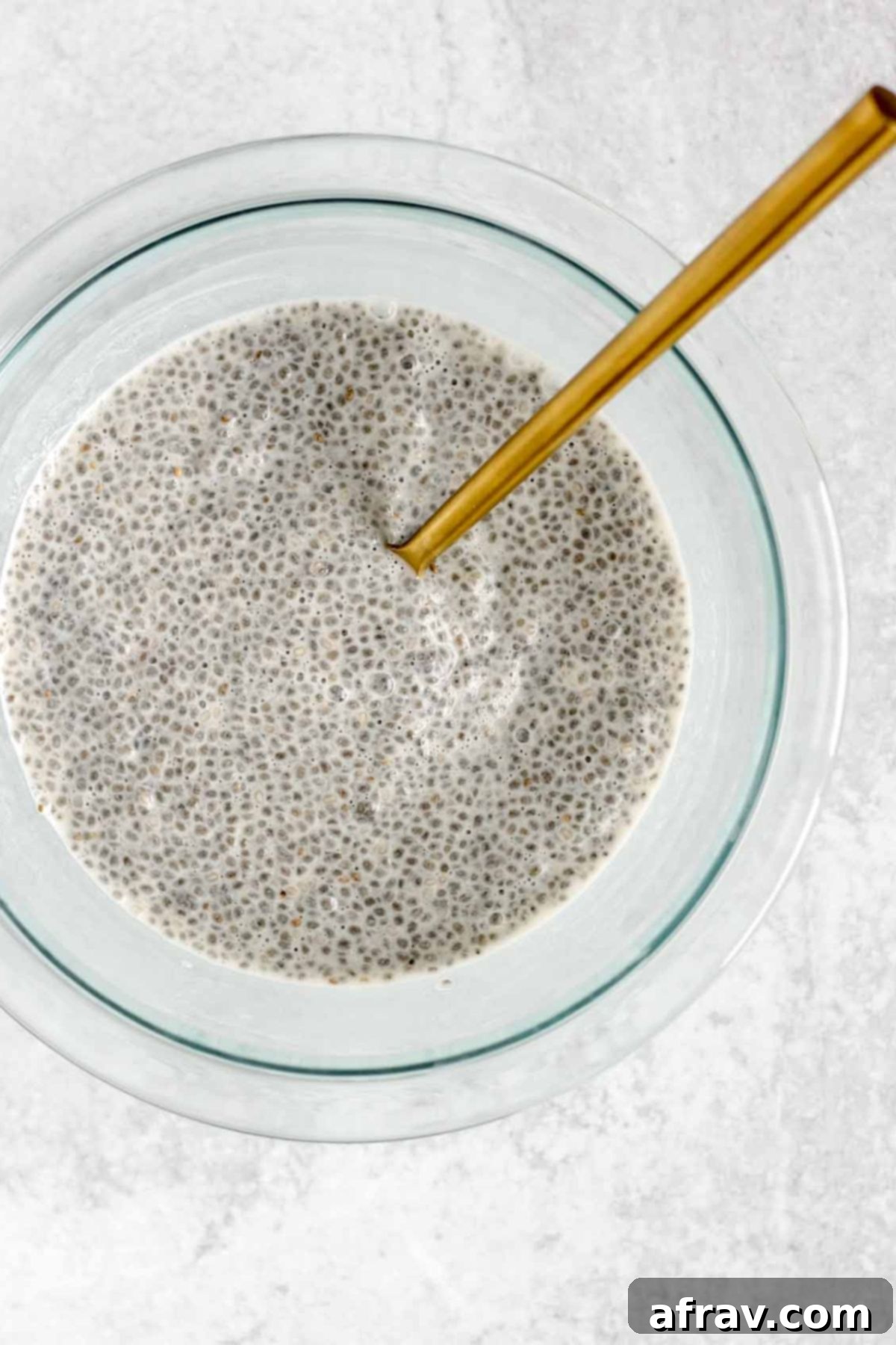 Chia seeds soaked in milk in a small glass mixing bowl.