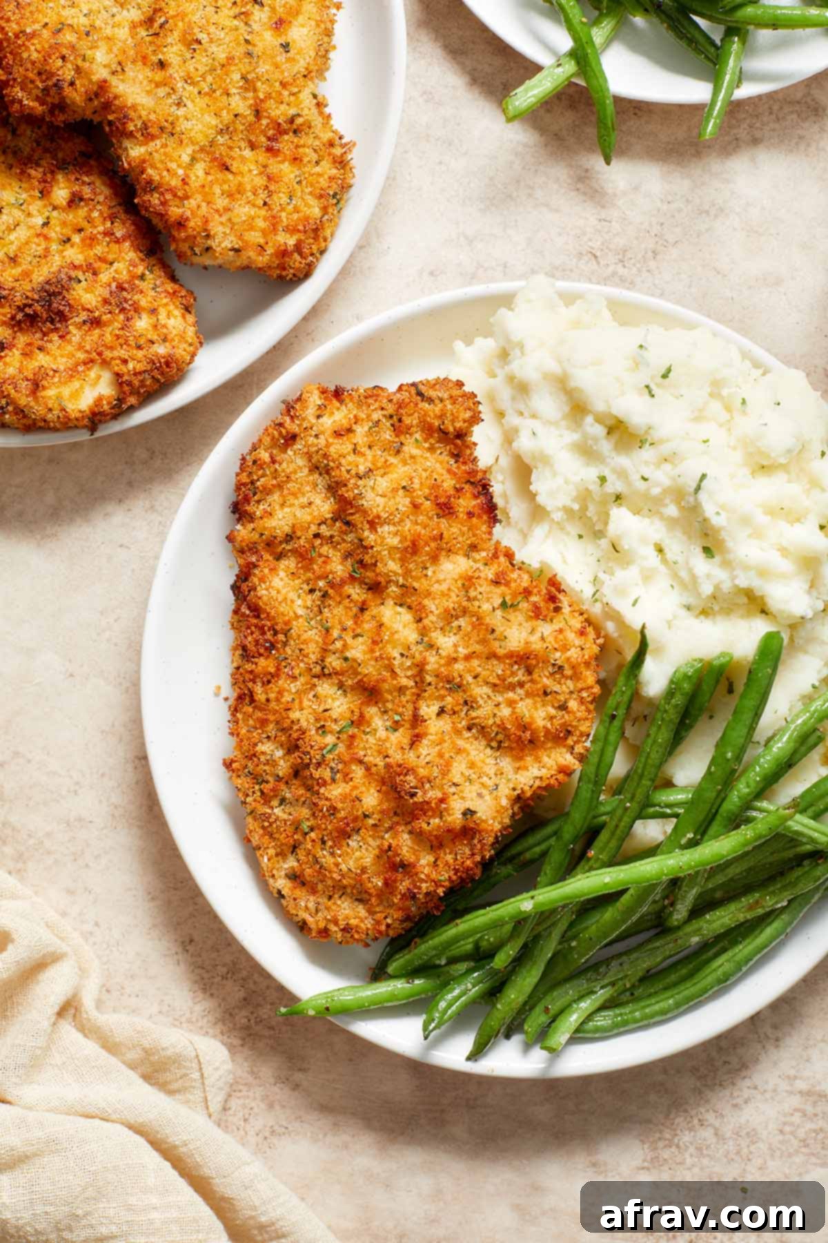 Close-up view of a golden-brown Air Fryer Chicken Schnitzel served on a pristine white plate, garnished with a fresh lemon wedge.