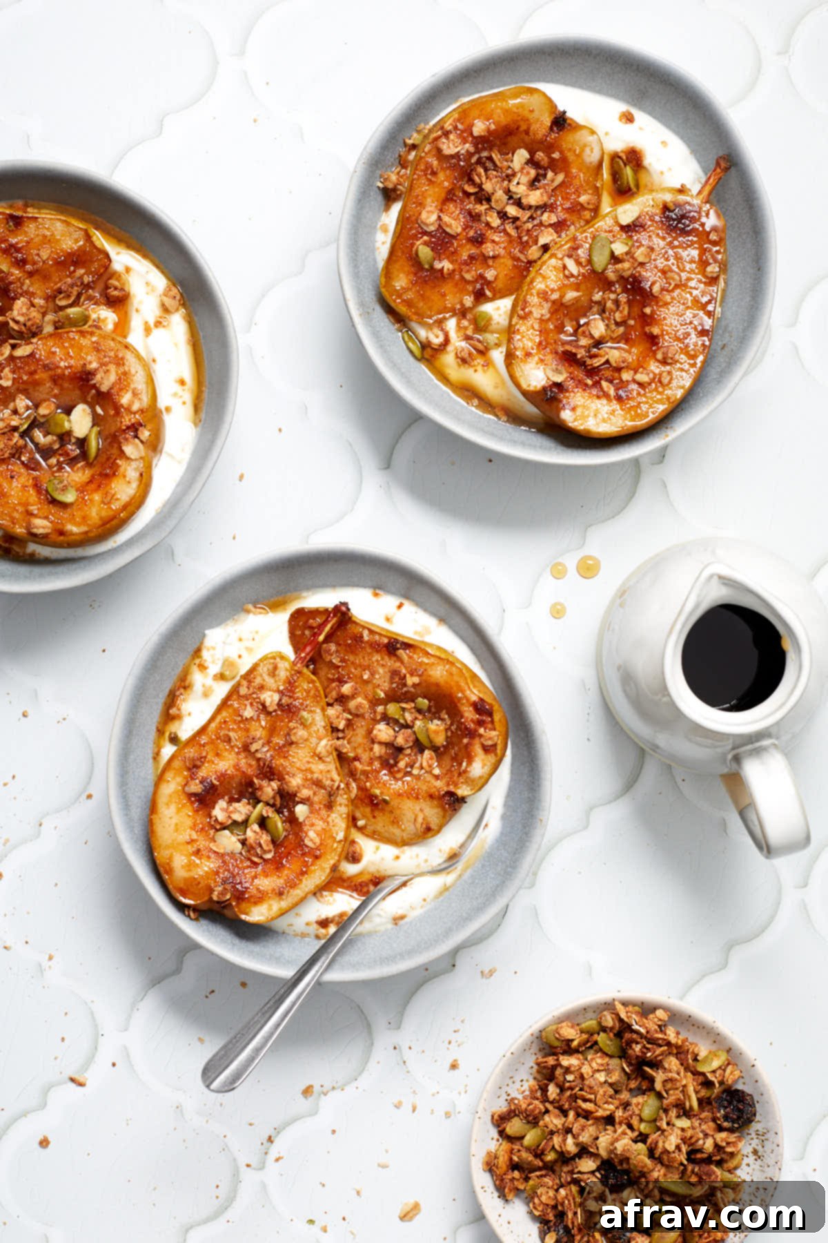 Sweet Air-Fried Pears 6 Three bowls of yogurt and baked pears arranged on a light coloured surface next to a bowl of granola and maple syrup.