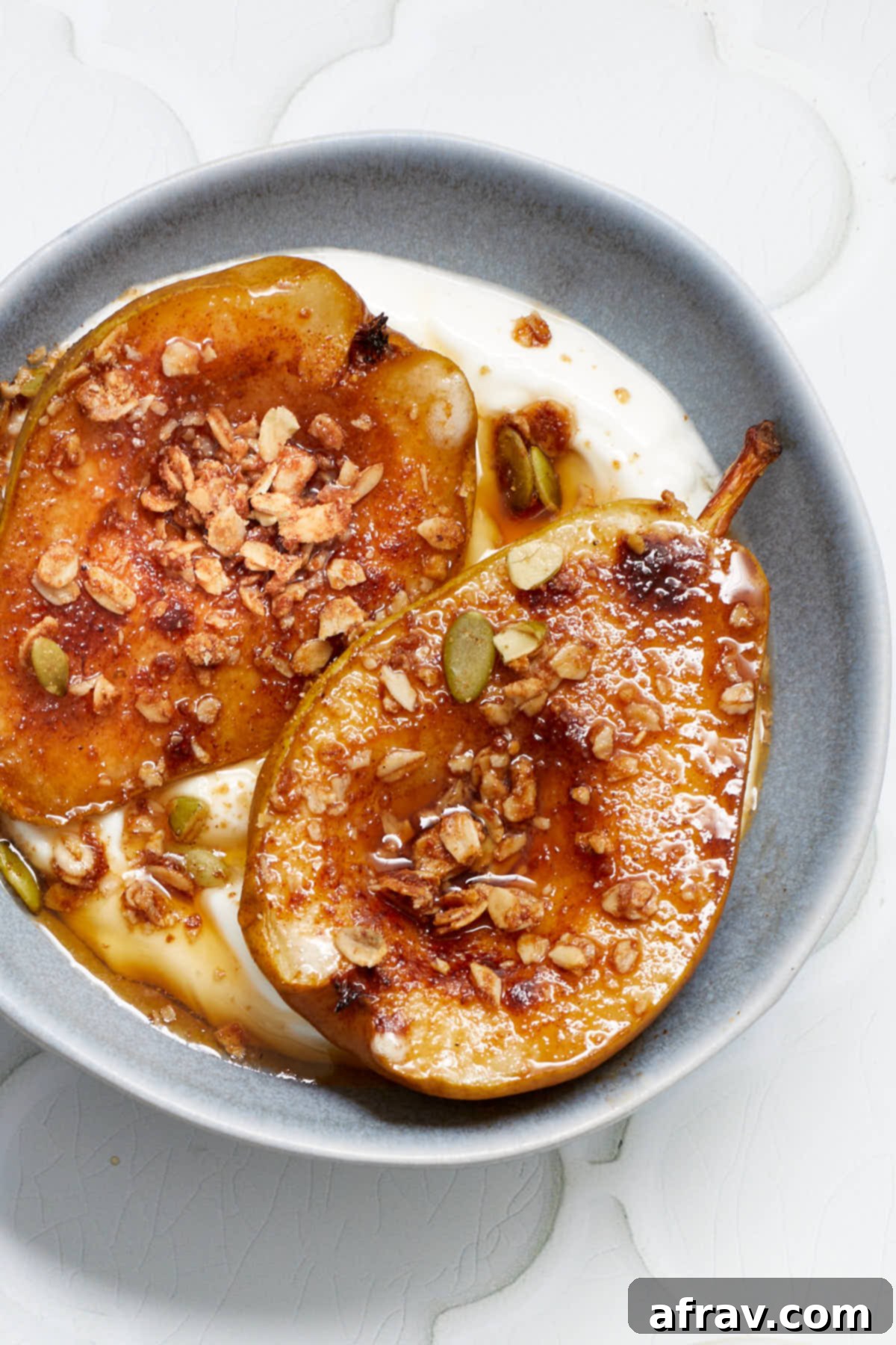 Sweet Air-Fried Pears 7 Close up view of air fried pear halves in a bowl with yogurt and granola sprinkled on top.