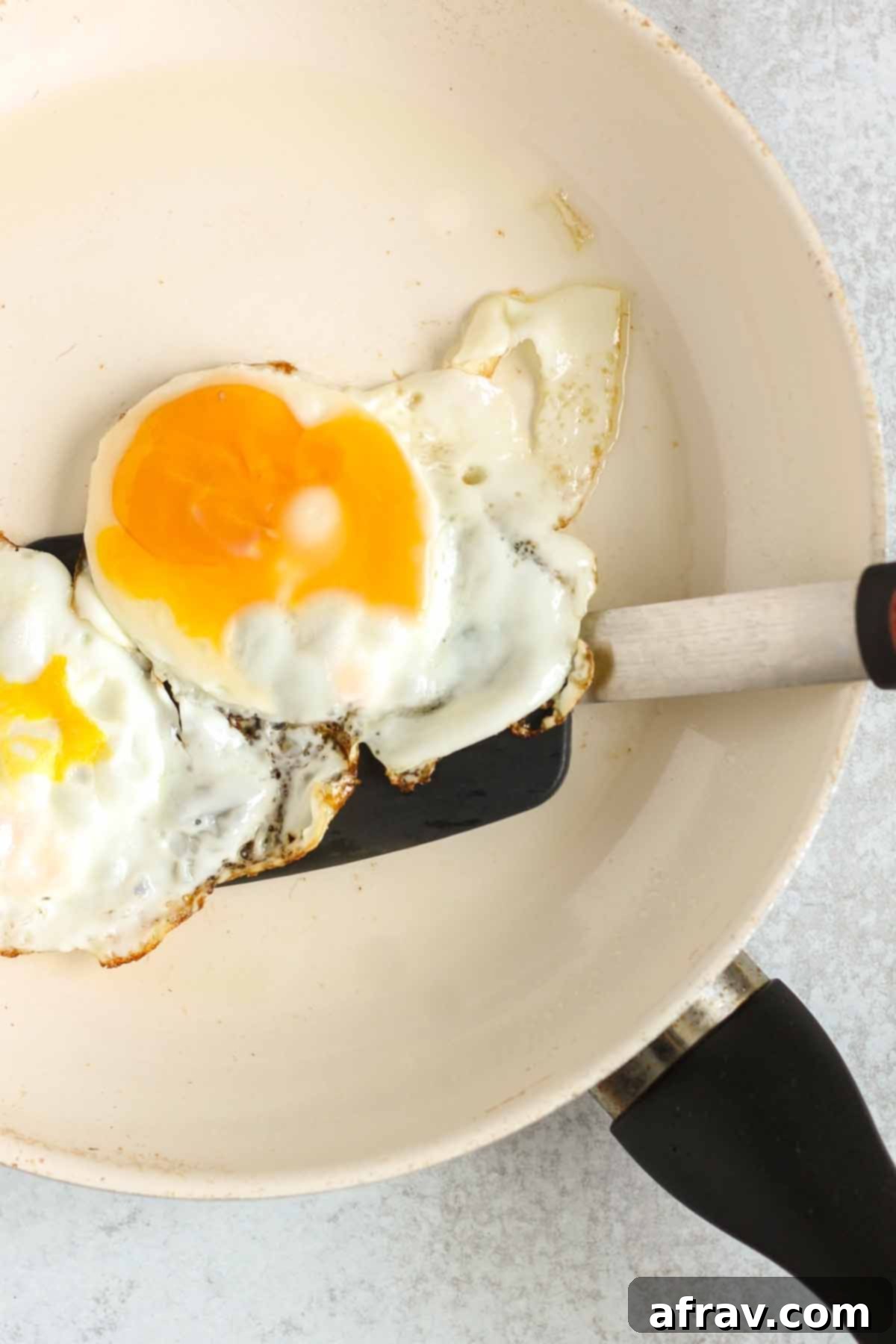 Fried eggs with a spatula in a frying pan.
