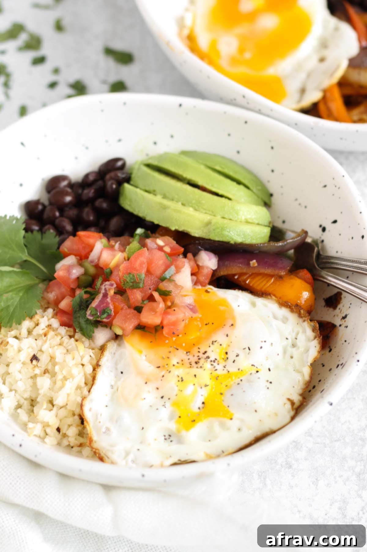 Breakfast burrito bowl with two forks in a speckled bowl.