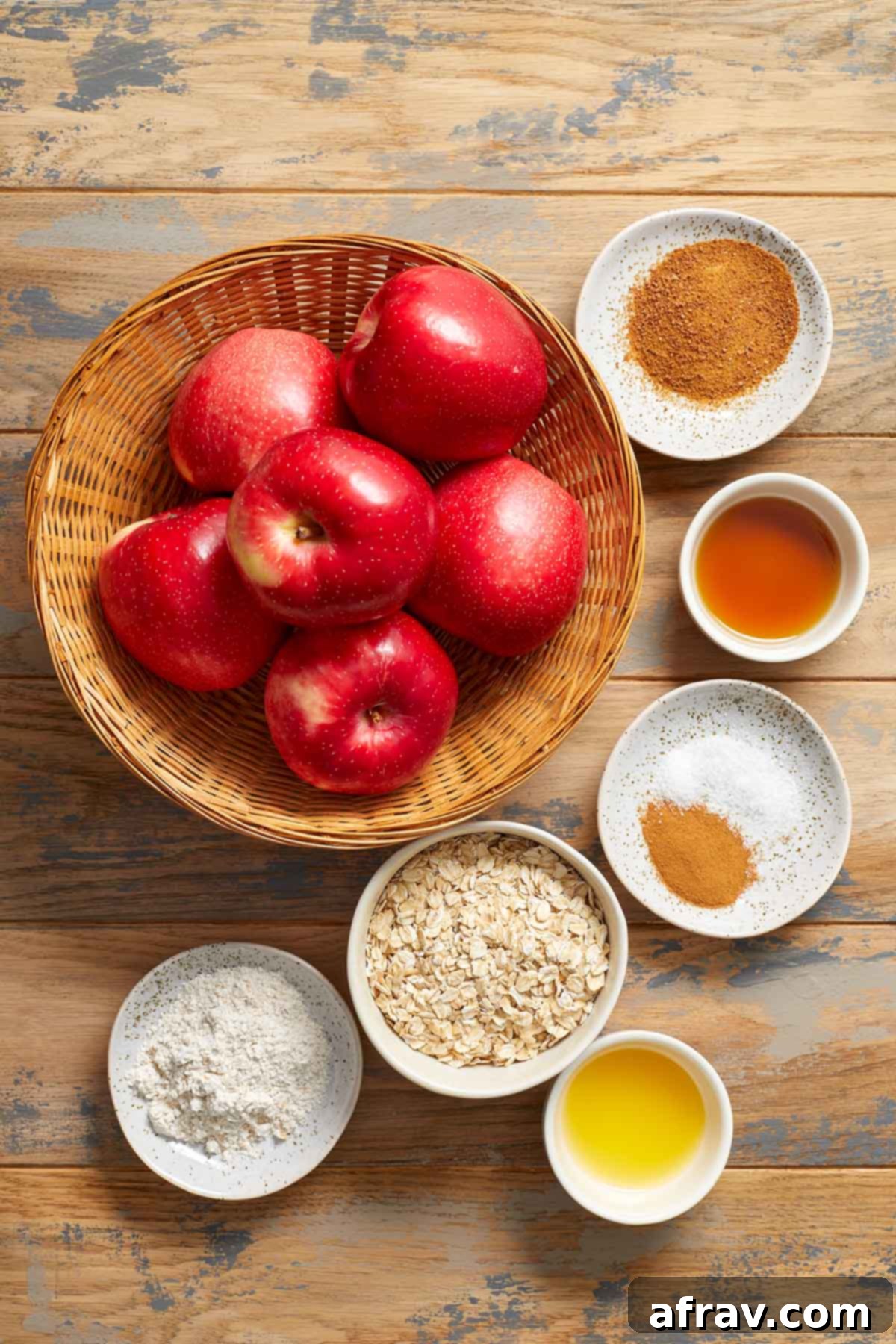 All the fresh and pantry ingredients laid out individually on a rustic wooden surface, ready to make air fryer baked apples.