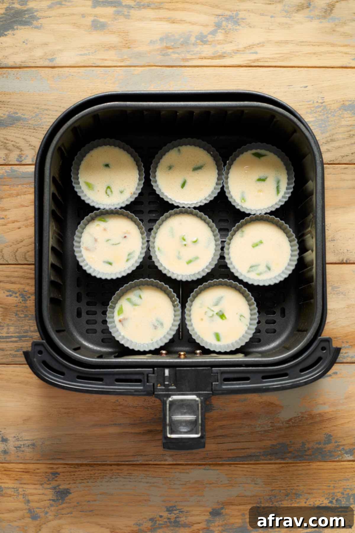 Silicone muffin cups filled with egg mixture and placed in the air fryer basket.