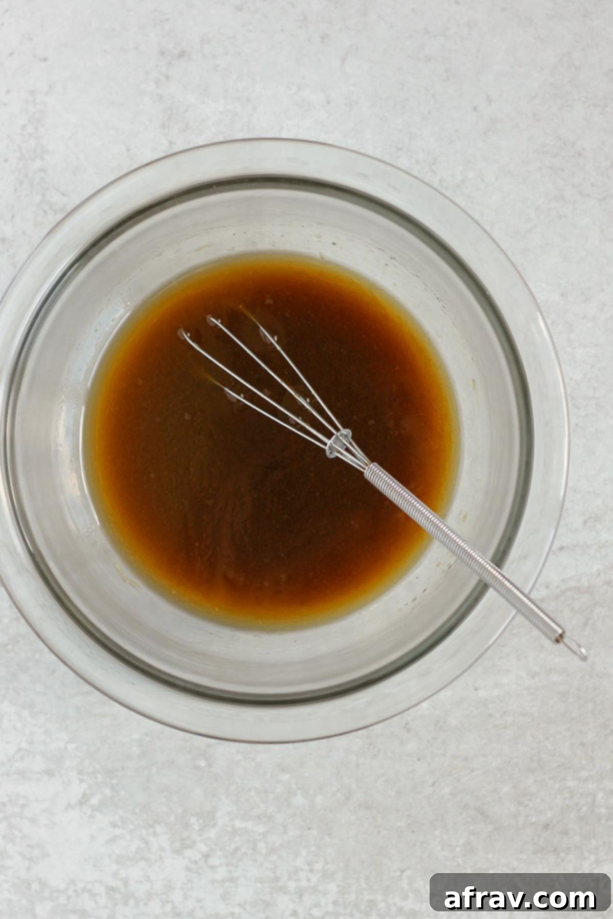 Asian cabbage salad dressing with a wire whisk in a glass mixing bowl.