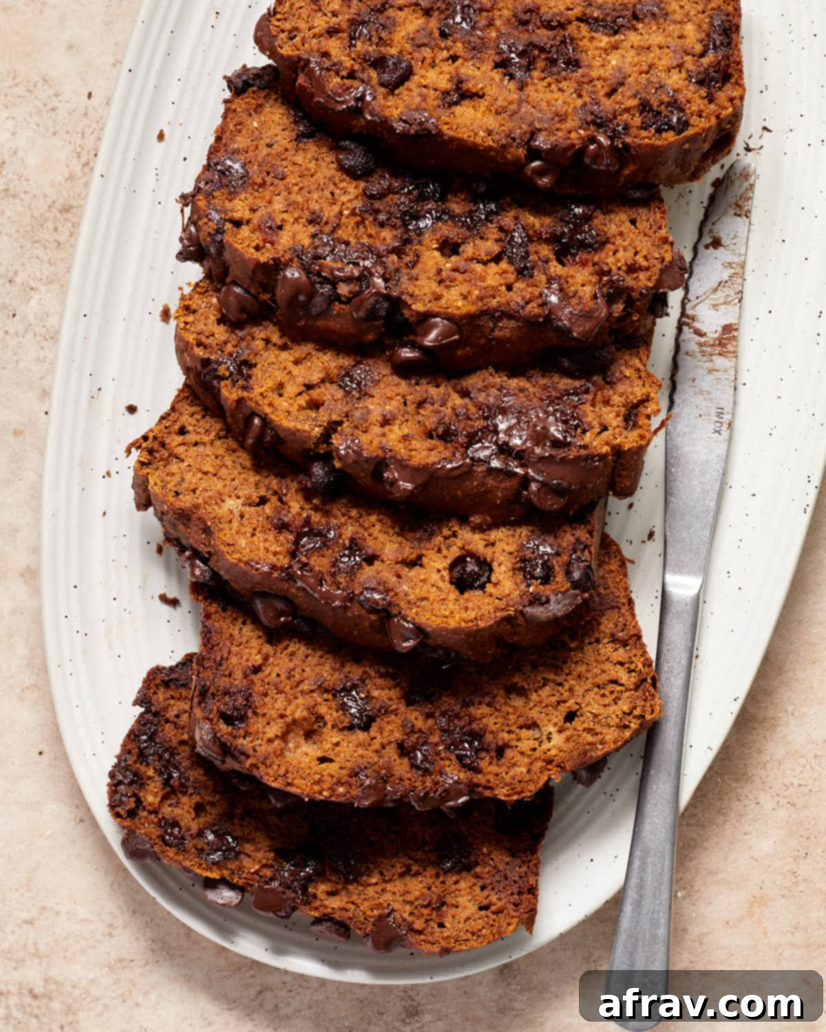 Moist Dairy Free Pumpkin Banana Bread 2 Close up view of perfectly baked slices of chocolate chip pumpkin banana bread on a rustic white platter, showcasing its moist texture and chocolate chunks.