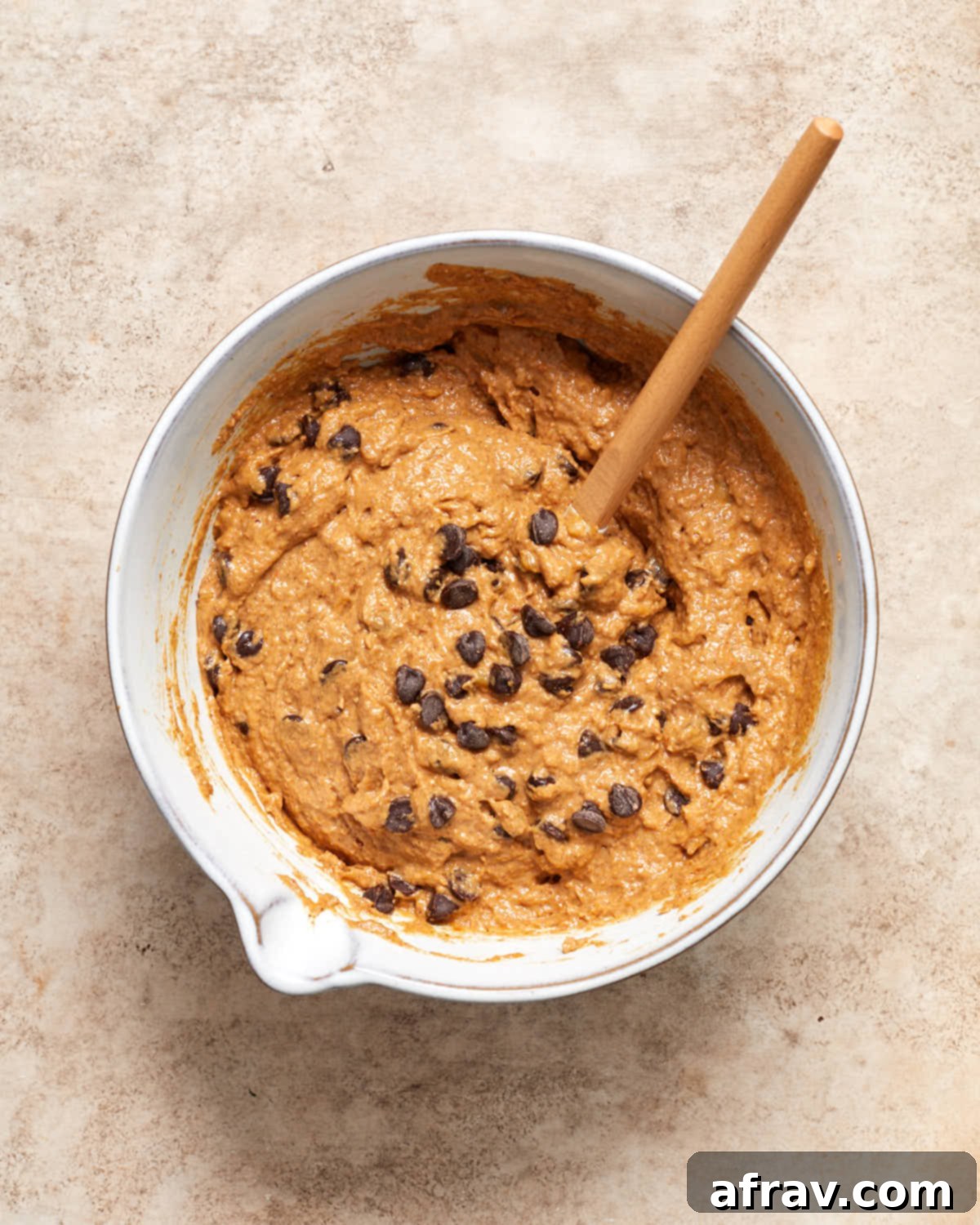 Moist Dairy Free Pumpkin Banana Bread 5 Pumpkin banana bread batter in a bowl with chocolate chips stirred into it using a spatula, showing the rich texture.