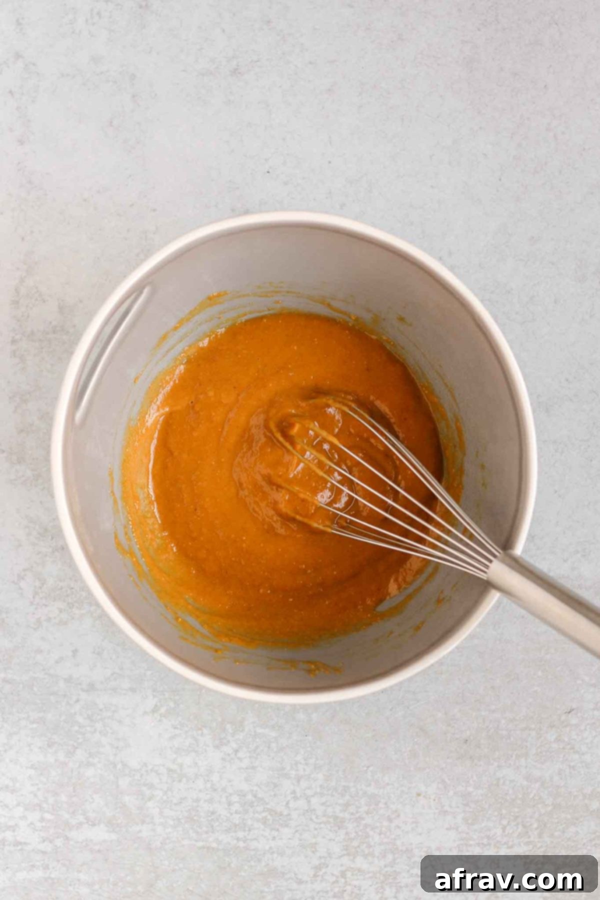 Grab-and-Go Pumpkin Breakfast Cookies 4 Wet ingredients for pumpkin breakfast cookies being whisked together in a medium-sized mixing bowl.