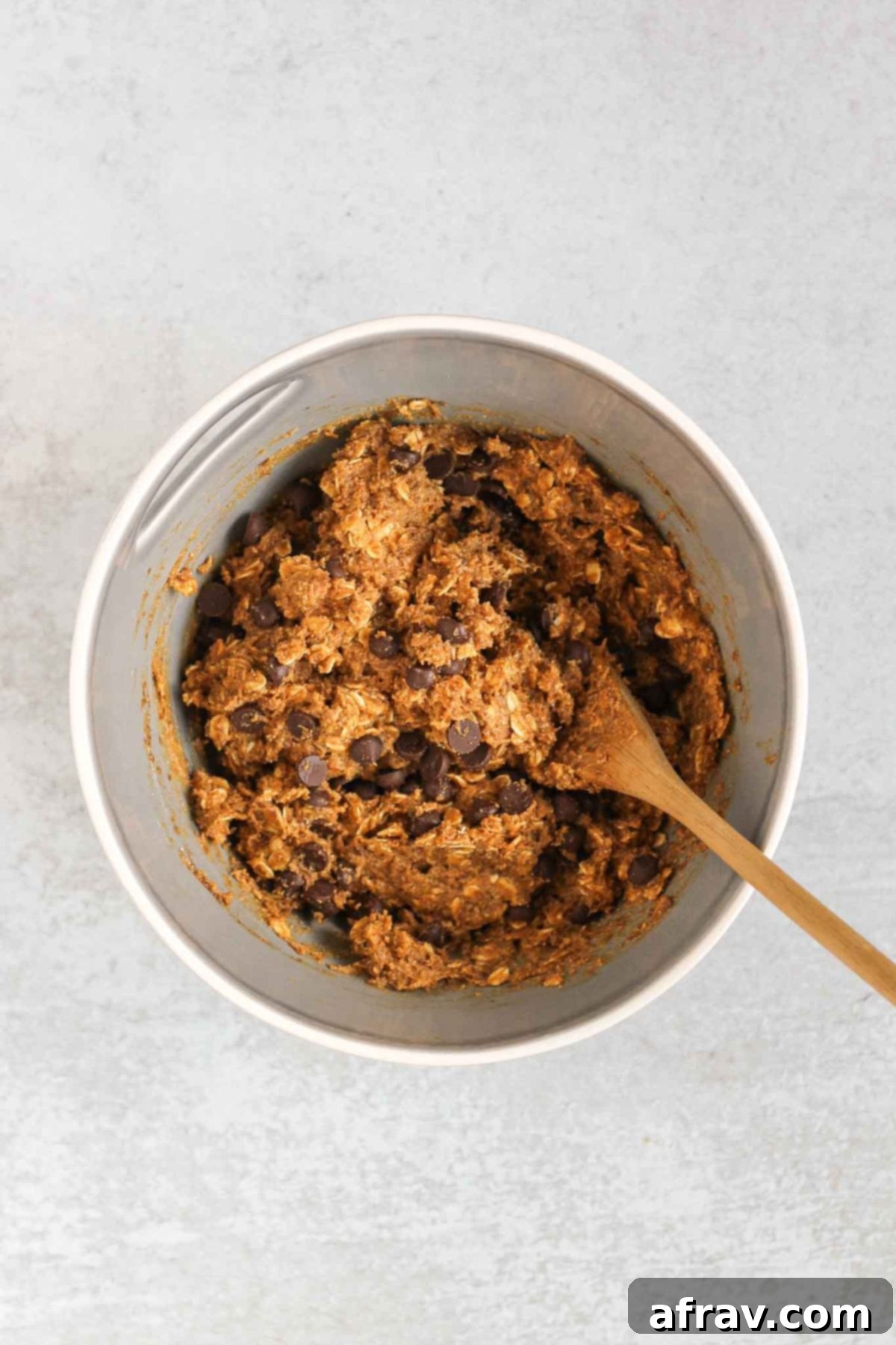 Grab-and-Go Pumpkin Breakfast Cookies 6 Chocolate chips being folded into pumpkin breakfast cookie dough with a spatula.