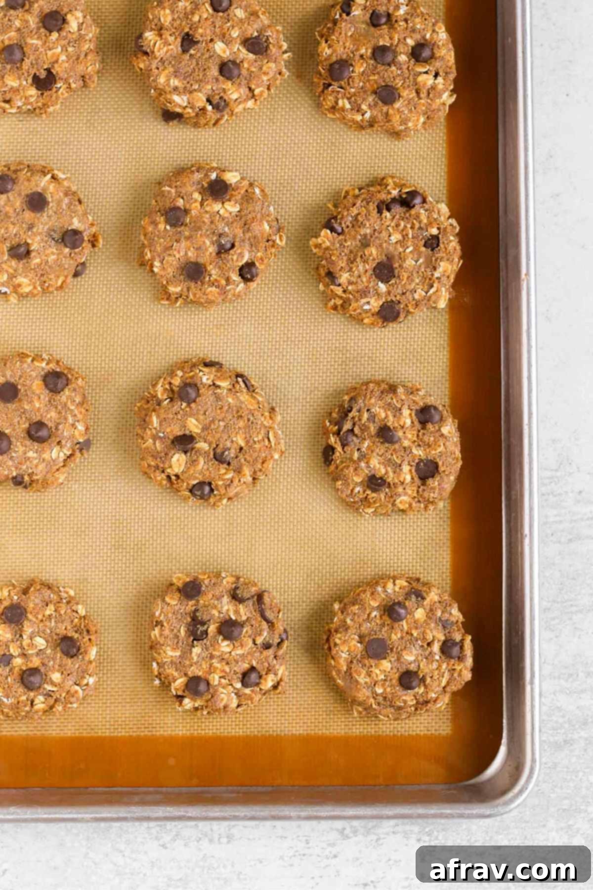 Grab-and-Go Pumpkin Breakfast Cookies 8 Raw pumpkin breakfast cookie dough shaped into perfectly round cookies on a baking sheet.