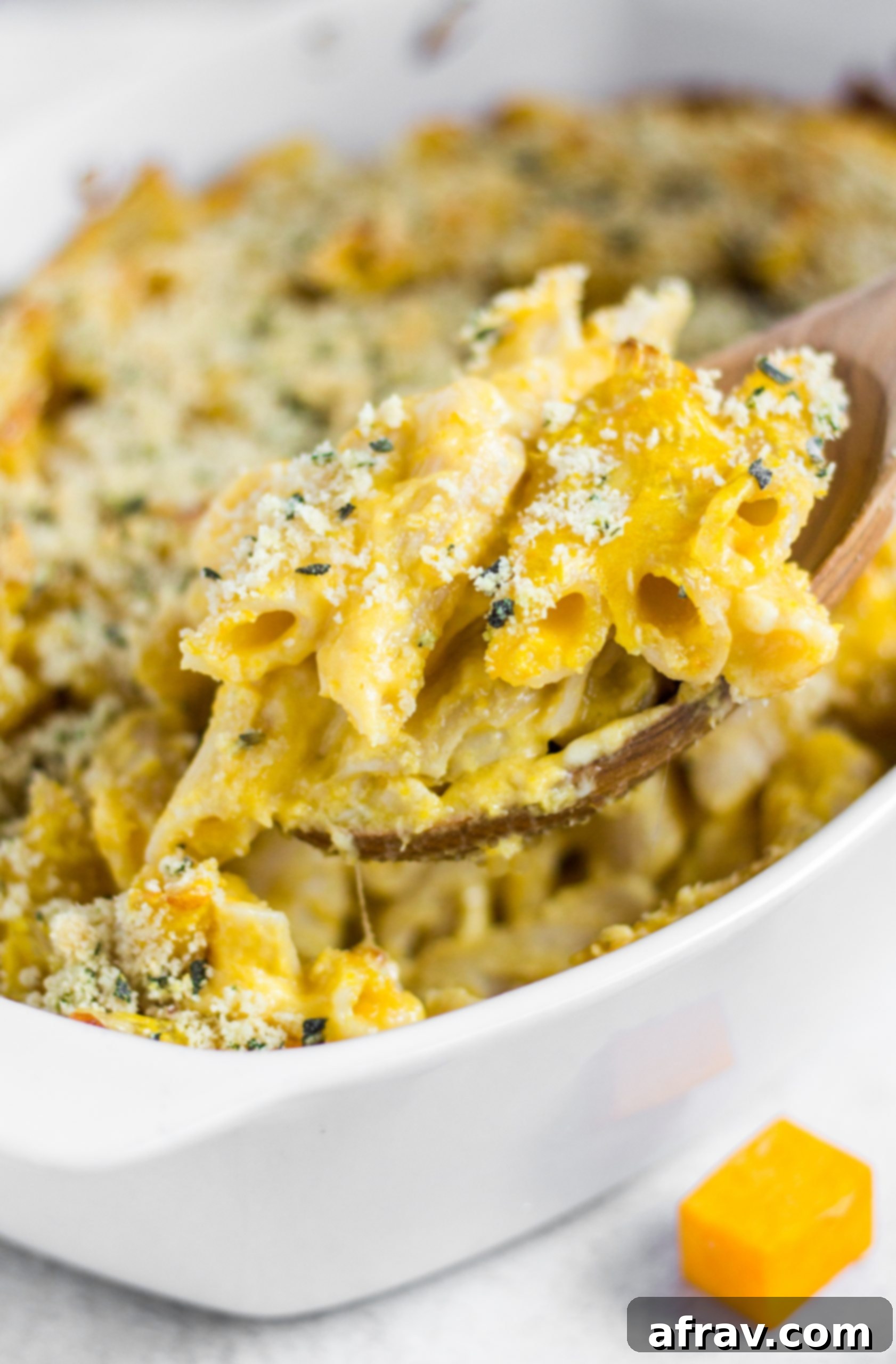 A close-up shot of gluten-free butternut squash mac and cheese being scooped from a baking dish, showcasing its rich, creamy texture.