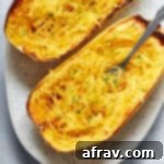 Air fryer spaghetti squash halves on a platter with a fork inserted into some noodles, highlighting the finished dish.