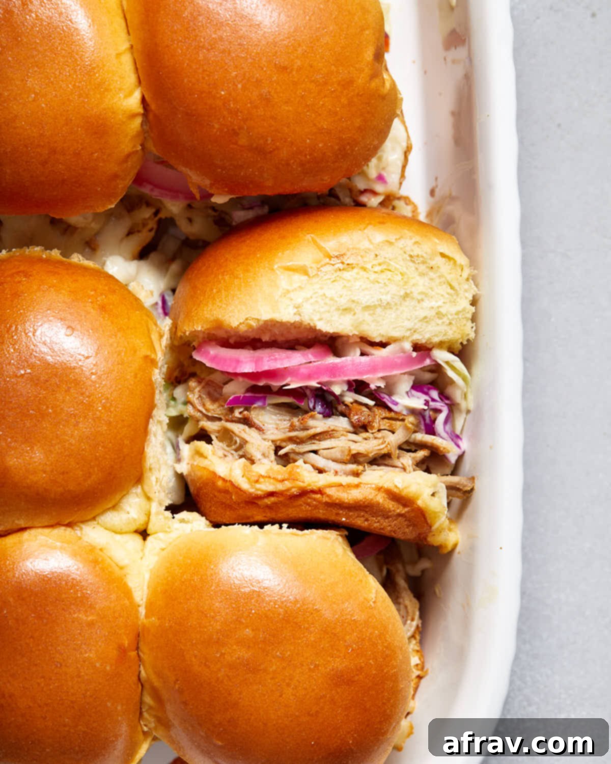 Pulled pork sliders in a white dish, showcasing the tender meat and soft buns.