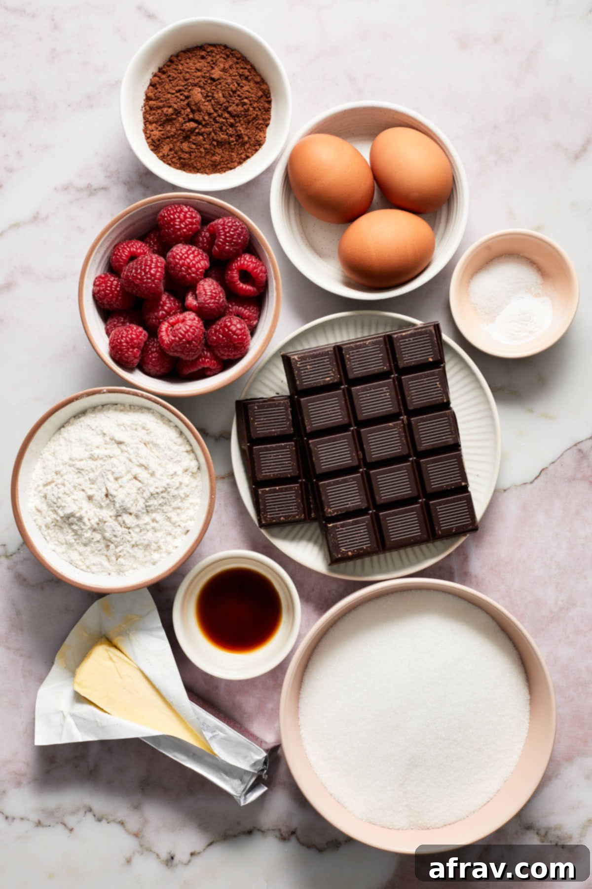 Ingredients to make chocolate raspberry brownies arranged on a marble-like surface, ready for baking.