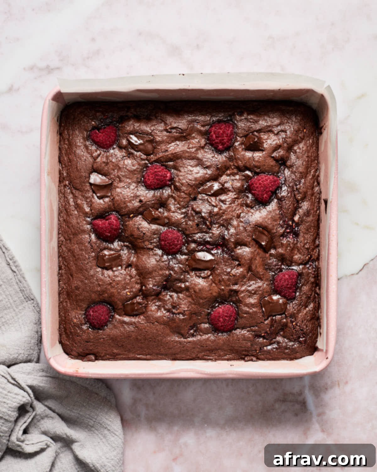 Freshly baked raspberry brownies still in the square baking pan, showing a perfectly set top crust.