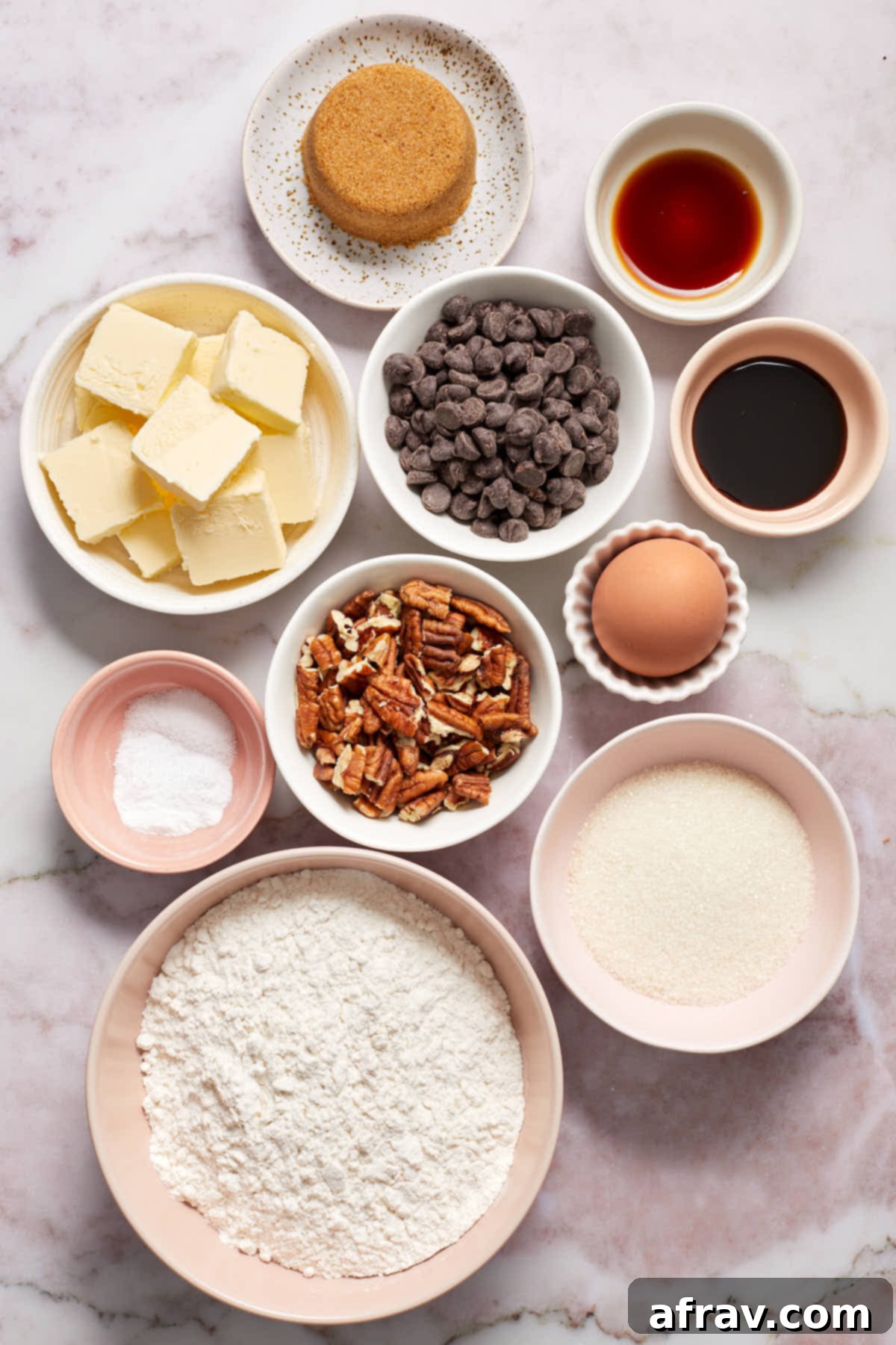 A flat lay of all the ingredients needed to make chocolate chip pecan cookies, neatly arranged on a white surface.