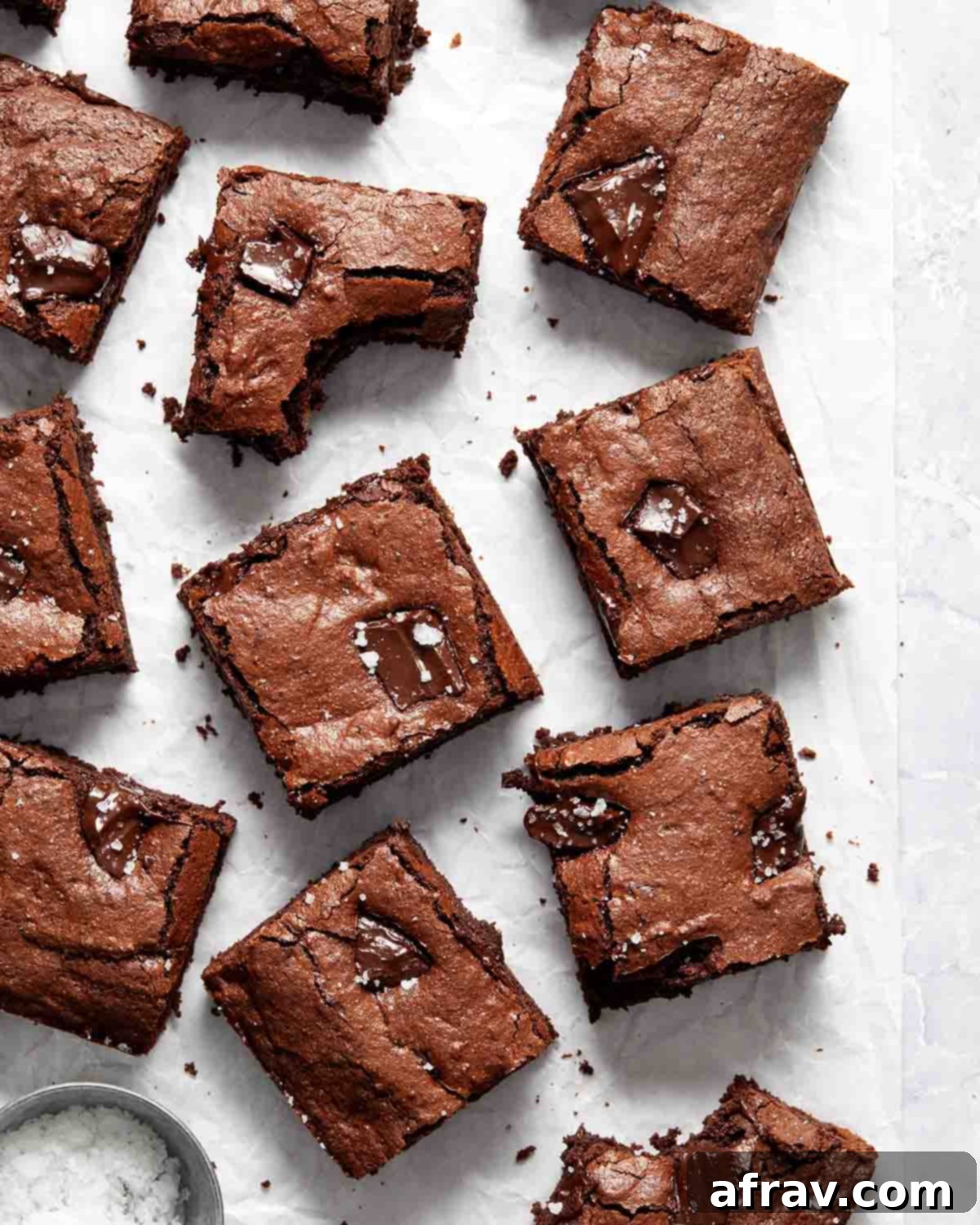 Fudgy Oat Flour Brownies 2 Brownies arranged on white parchment paper with a bite taken out of a few.