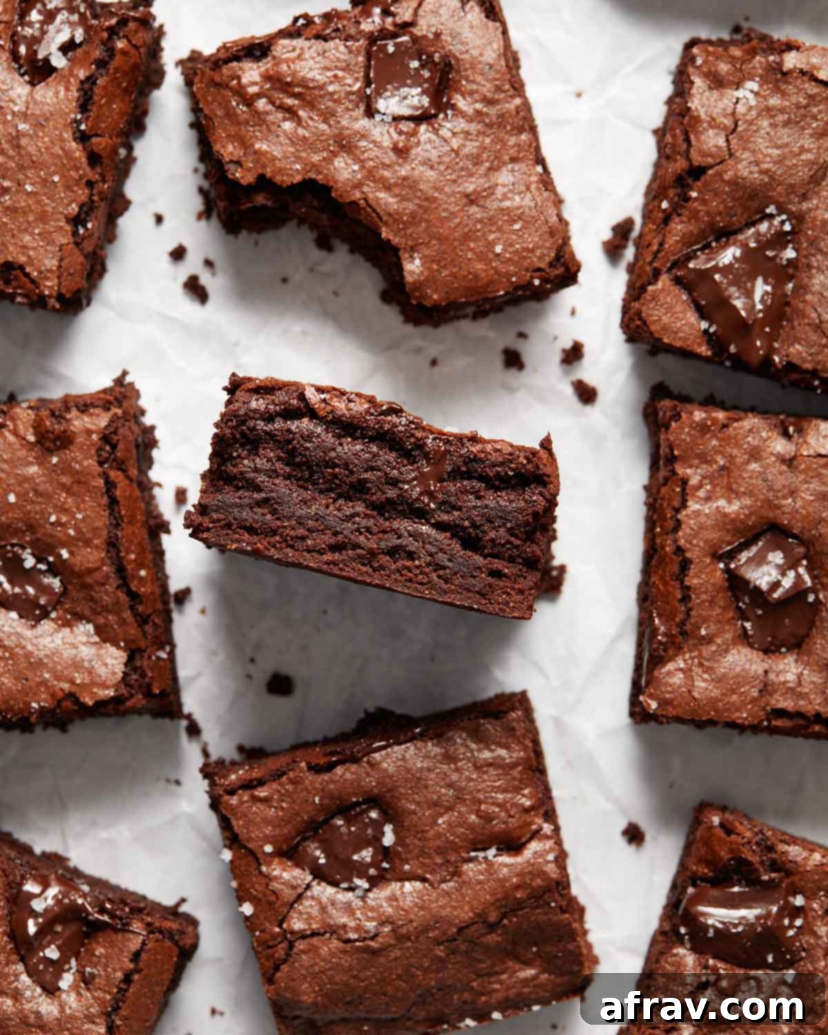 Fudgy Oat Flour Brownies 3 Overhead view of brownies on parchment paper with one turned on its side to expose the fudgy texture.