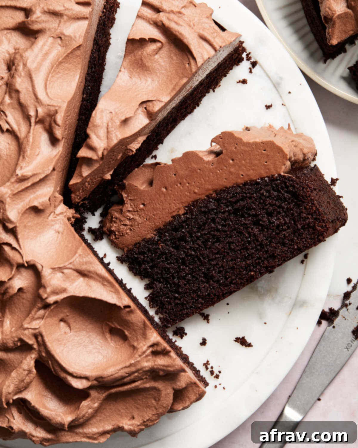 Overhead view of the sliced almond flour chocolate cake on a white marble cake plate, showcasing its moist texture and chocolate whipped cream.