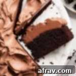 Close up view of a slice of almond flour chocolate cake on a white marble cake plate.